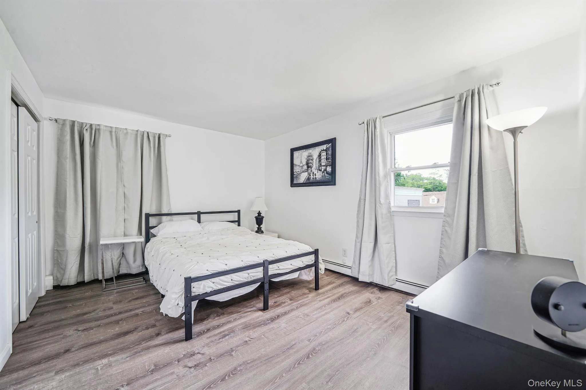 Bedroom featuring light wood-style flooring and baseboard heating Bedroom featuring light wood-style flooring and baseboard heating