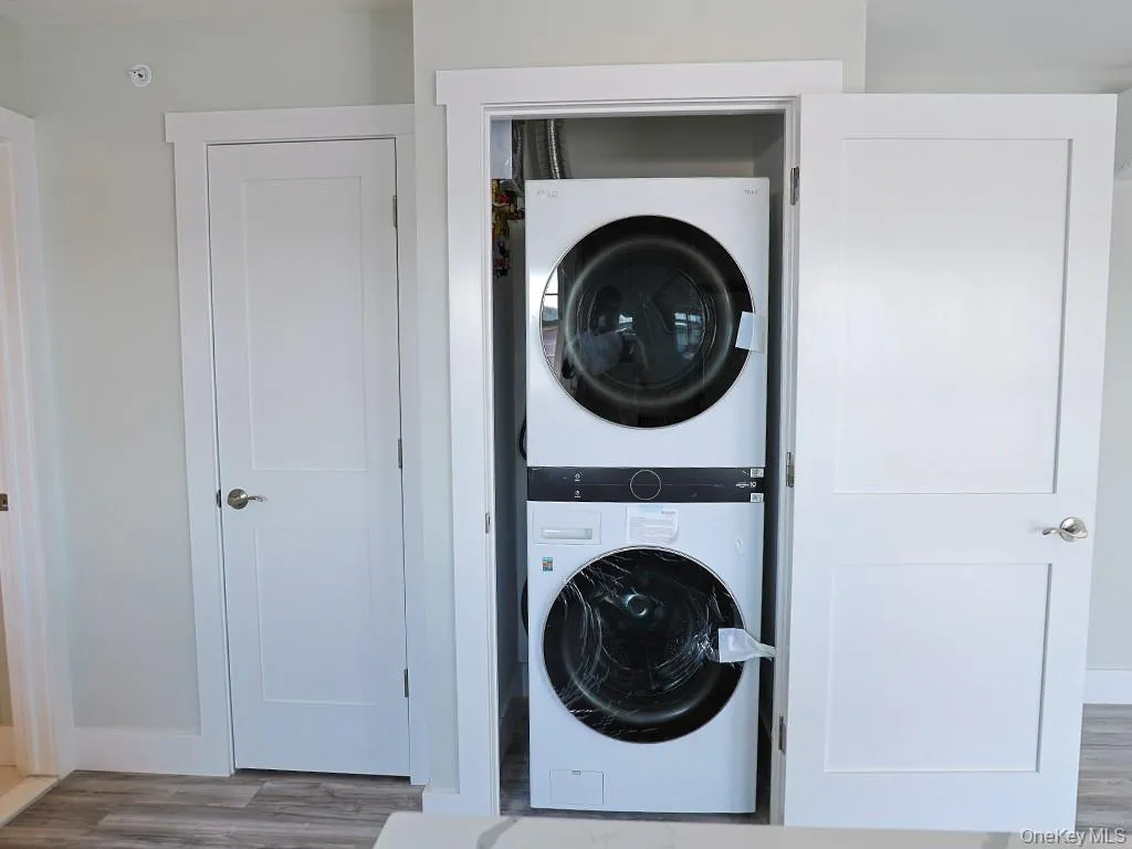 Laundry room with stacked washer / dryer and wood finished floors Laundry room with stacked washer / dryer and wood finished floors