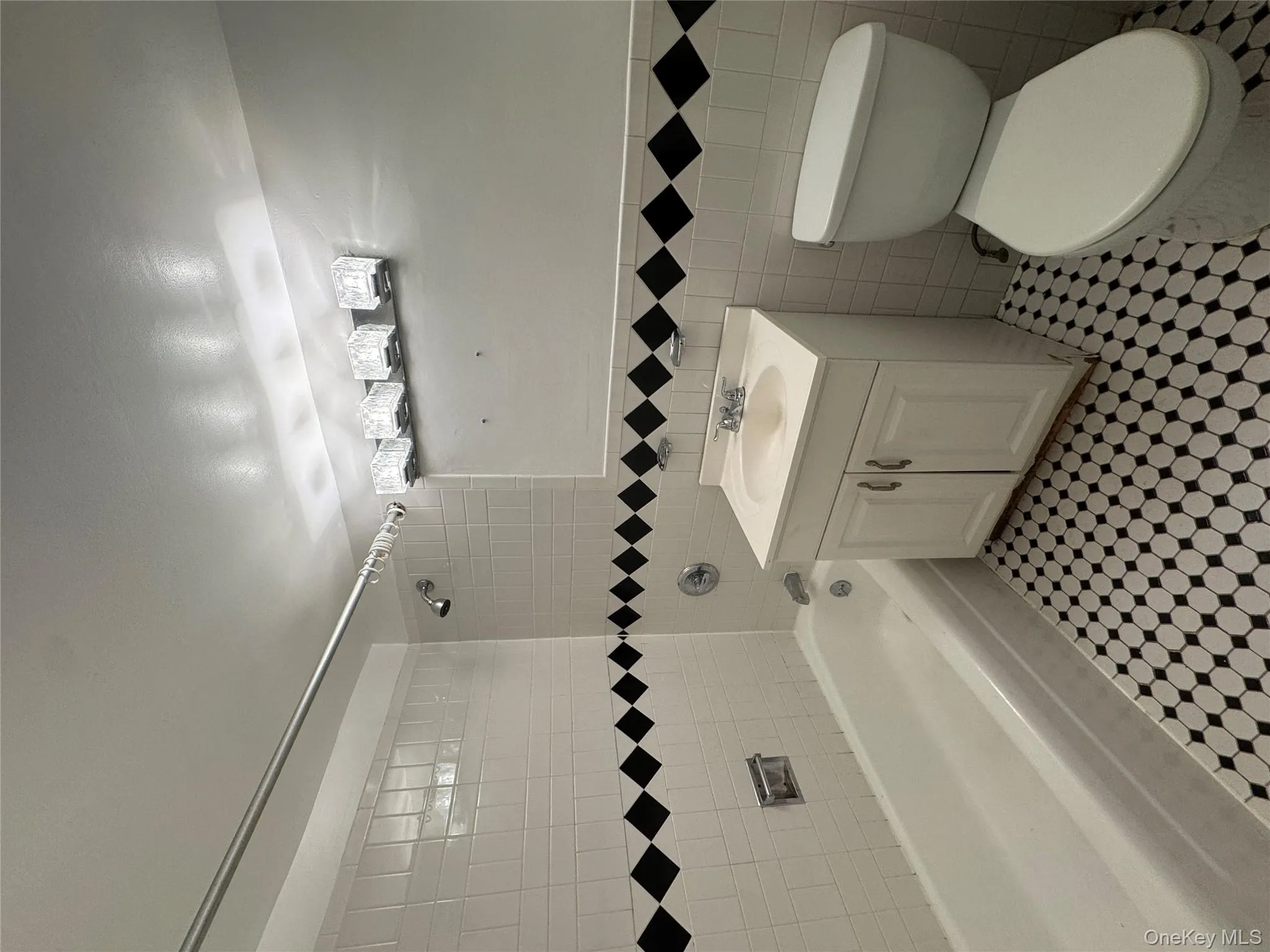 Bathroom featuring washtub / shower combination, vanity, tile walls, and light tile patterned flooring Bathroom featuring washtub / shower combination, vanity, tile walls, and light tile patterned flooring