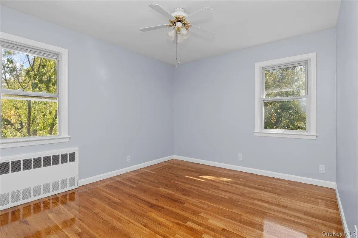 Unfurnished room with radiator, light wood-style flooring, and ceiling fan Unfurnished room with radiator, light wood-style flooring, and ceiling fan