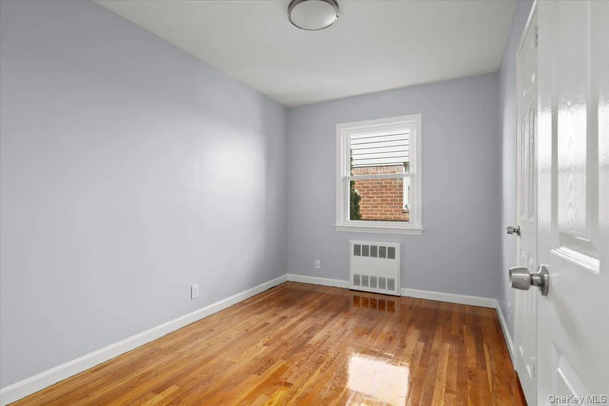 Unfurnished room featuring light wood-style floors and radiator Unfurnished room featuring light wood-style floors and radiator
