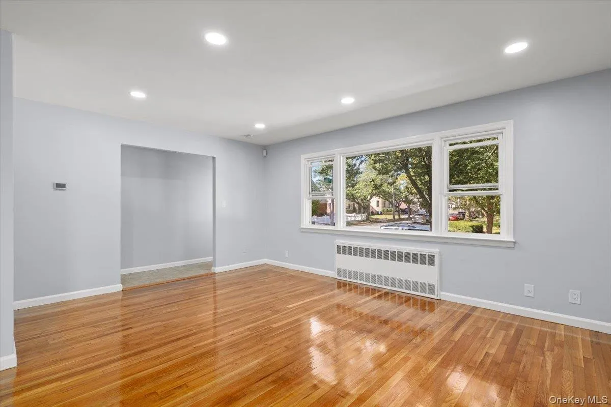 Unfurnished room featuring radiator heating unit, recessed lighting, and light wood finished floors Unfurnished room featuring radiator heating unit, recessed lighting, and light wood finished floors