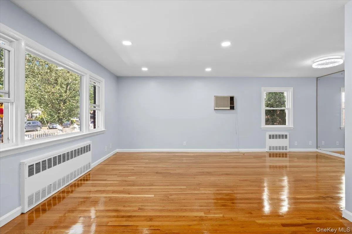 Unfurnished living room with radiator heating unit, recessed lighting, and light wood finished floors Unfurnished living room with radiator heating unit, recessed lighting, and light wood finished floors