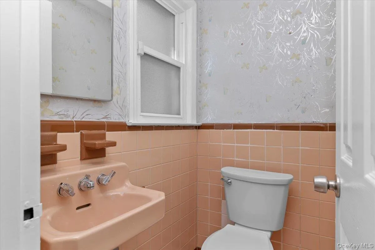Bathroom featuring wallpapered walls and tile walls Bathroom featuring wallpapered walls and tile walls