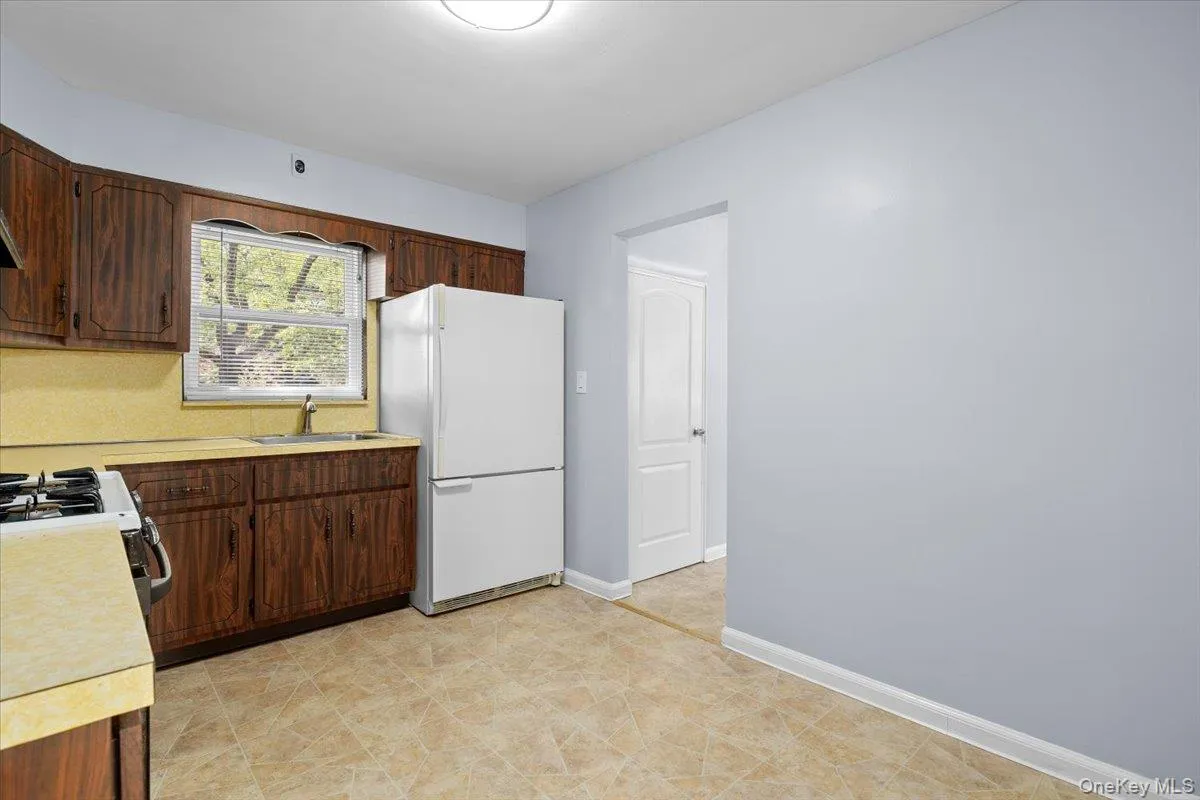 Kitchen featuring light countertops, white appliances, and dark brown cabinetry Kitchen featuring light countertops, white appliances, and dark brown cabinetry