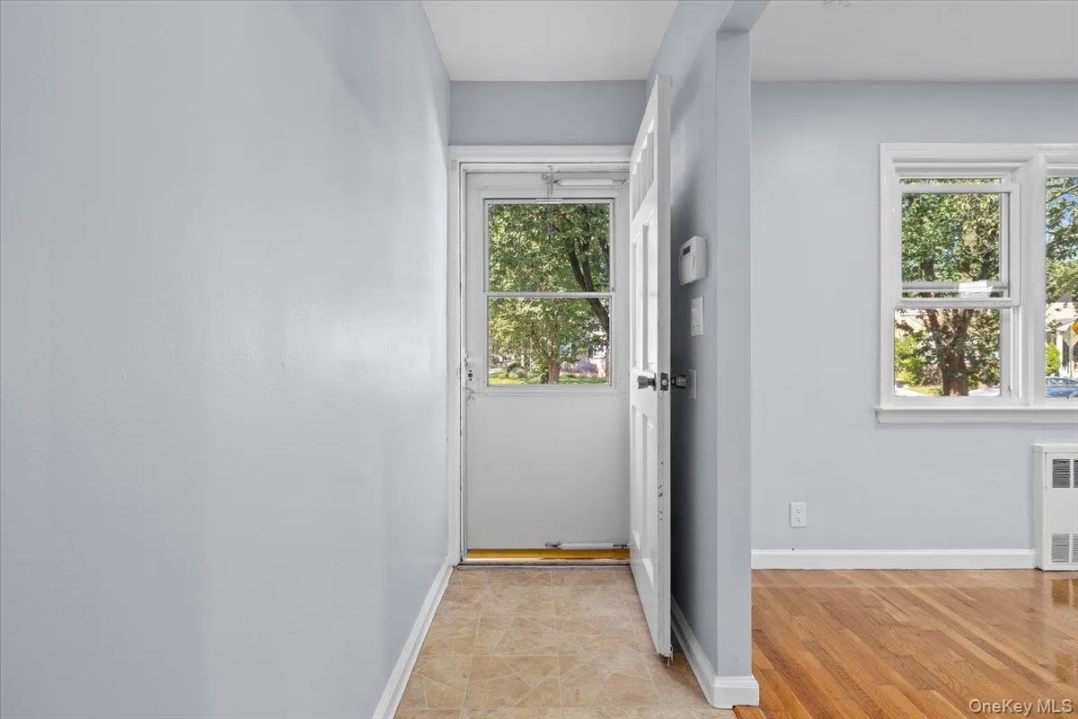 Doorway to outside with radiator heating unit and wood finished floors Doorway to outside with radiator heating unit and wood finished floors