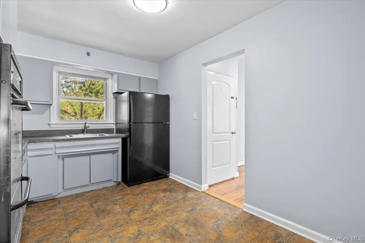 Kitchen featuring freestanding refrigerator, dark countertops, double oven, and stone finish floors Kitchen featuring freestanding refrigerator, dark countertops, double oven, and stone finish floors