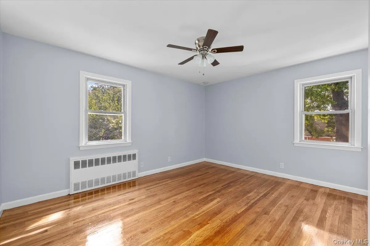 Empty room with radiator heating unit, healthy amount of natural light, and light wood-style flooring Empty room with radiator heating unit, healthy amount of natural light, and light wood-style flooring