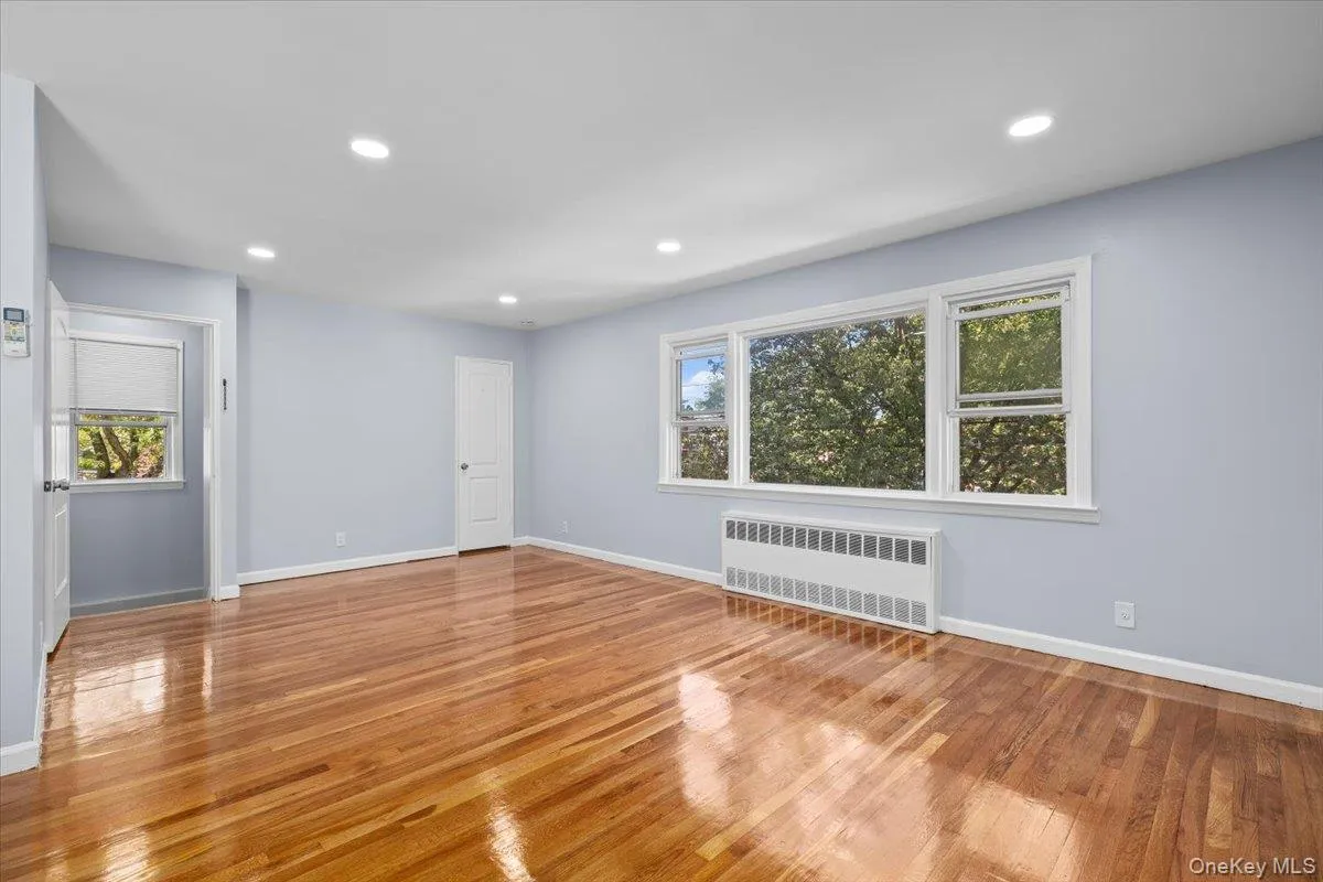 Unfurnished living room featuring radiator, recessed lighting, and light wood-style floors Unfurnished living room featuring radiator, recessed lighting, and light wood-style floors