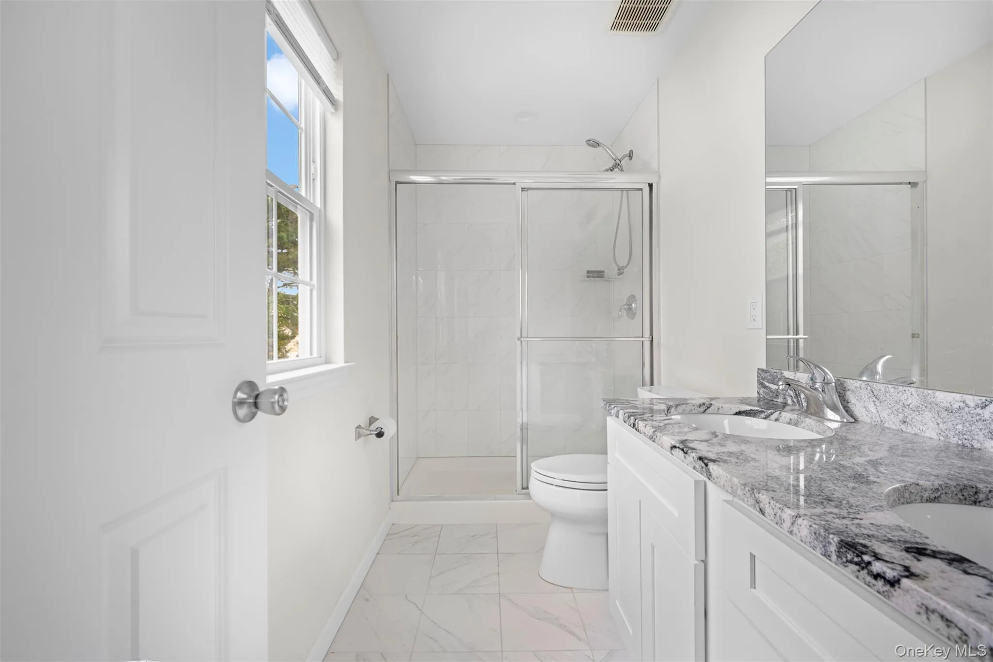 Bathroom with double vanity, a stall shower, and light marble finish flooring Bathroom with double vanity, a stall shower, and light marble finish flooring