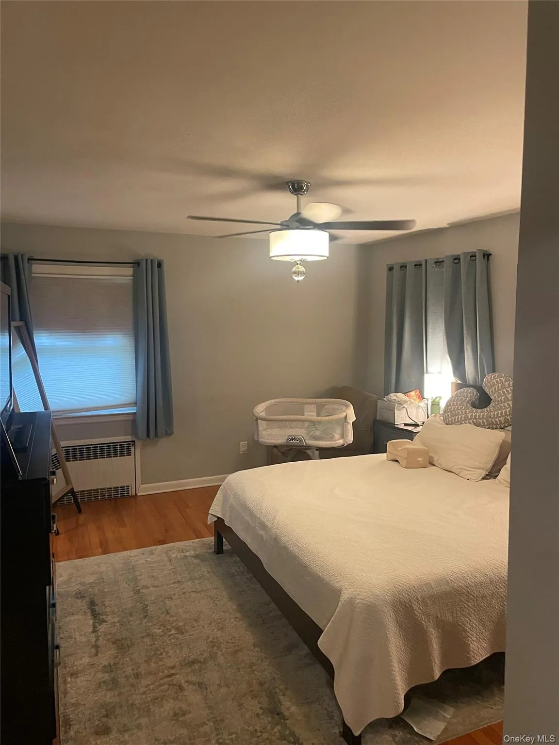 Bedroom with light wood finished floors, ceiling fan, and radiator Bedroom with light wood finished floors, ceiling fan, and radiator
