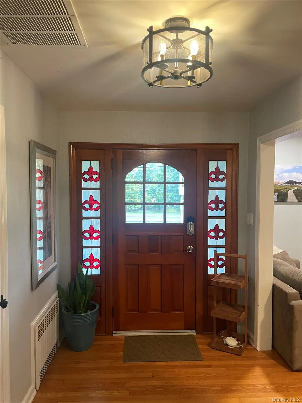 Foyer with radiator, light wood-style floors, and a chandelier Foyer with radiator, light wood-style floors, and a chandelier
