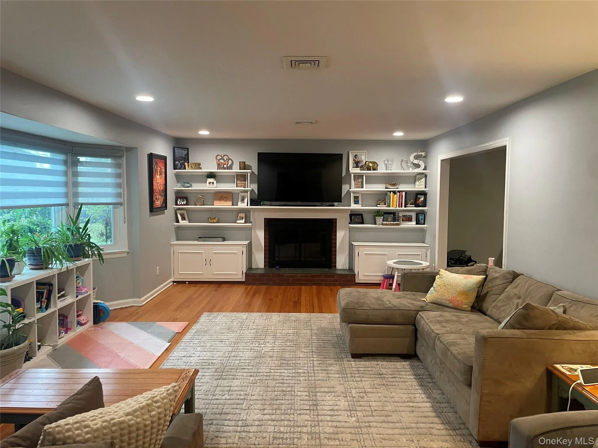 Living area featuring a brick fireplace, light wood-type flooring, and recessed lighting Living area featuring a brick fireplace, light wood-type flooring, and recessed lighting