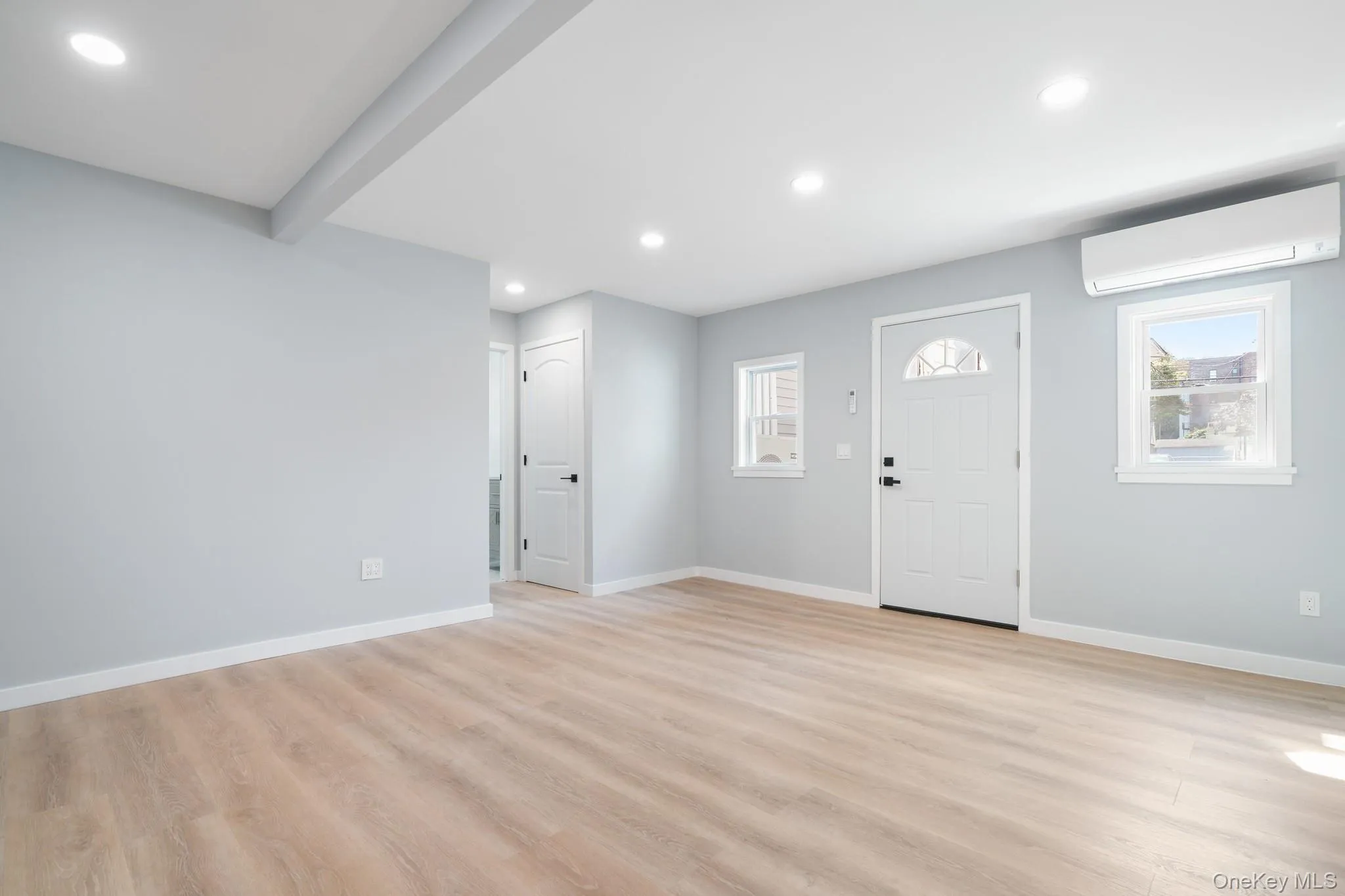 Foyer with light wood-type flooring, recessed lighting, a wall mounted AC, and beam ceiling Foyer with light wood-type flooring, recessed lighting, a wall mounted AC, and beam ceiling