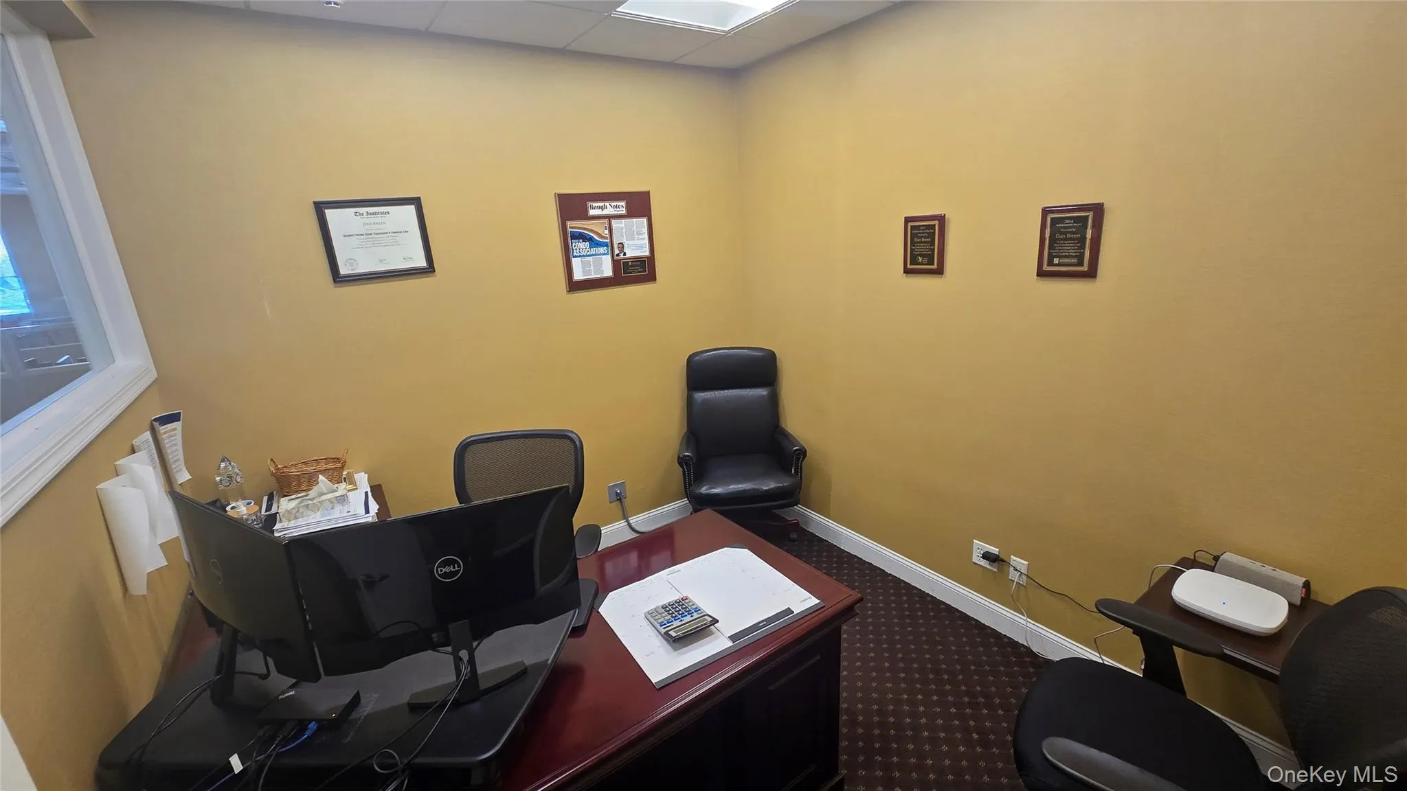 Office area featuring a drop ceiling and dark carpet Office area featuring a drop ceiling and dark carpet