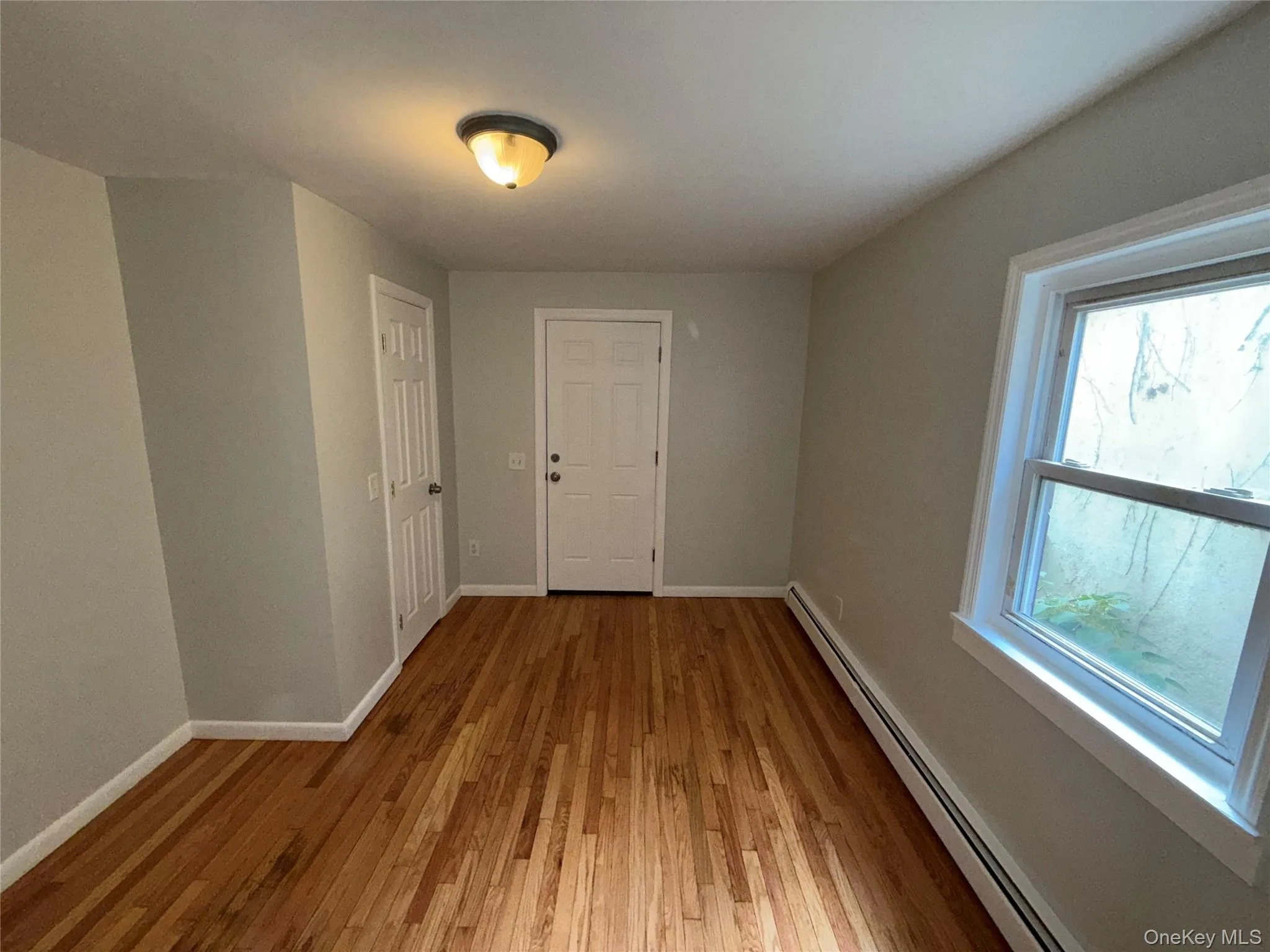 Hall with a baseboard heating unit and light wood-style flooring Hall with a baseboard heating unit and light wood-style flooring