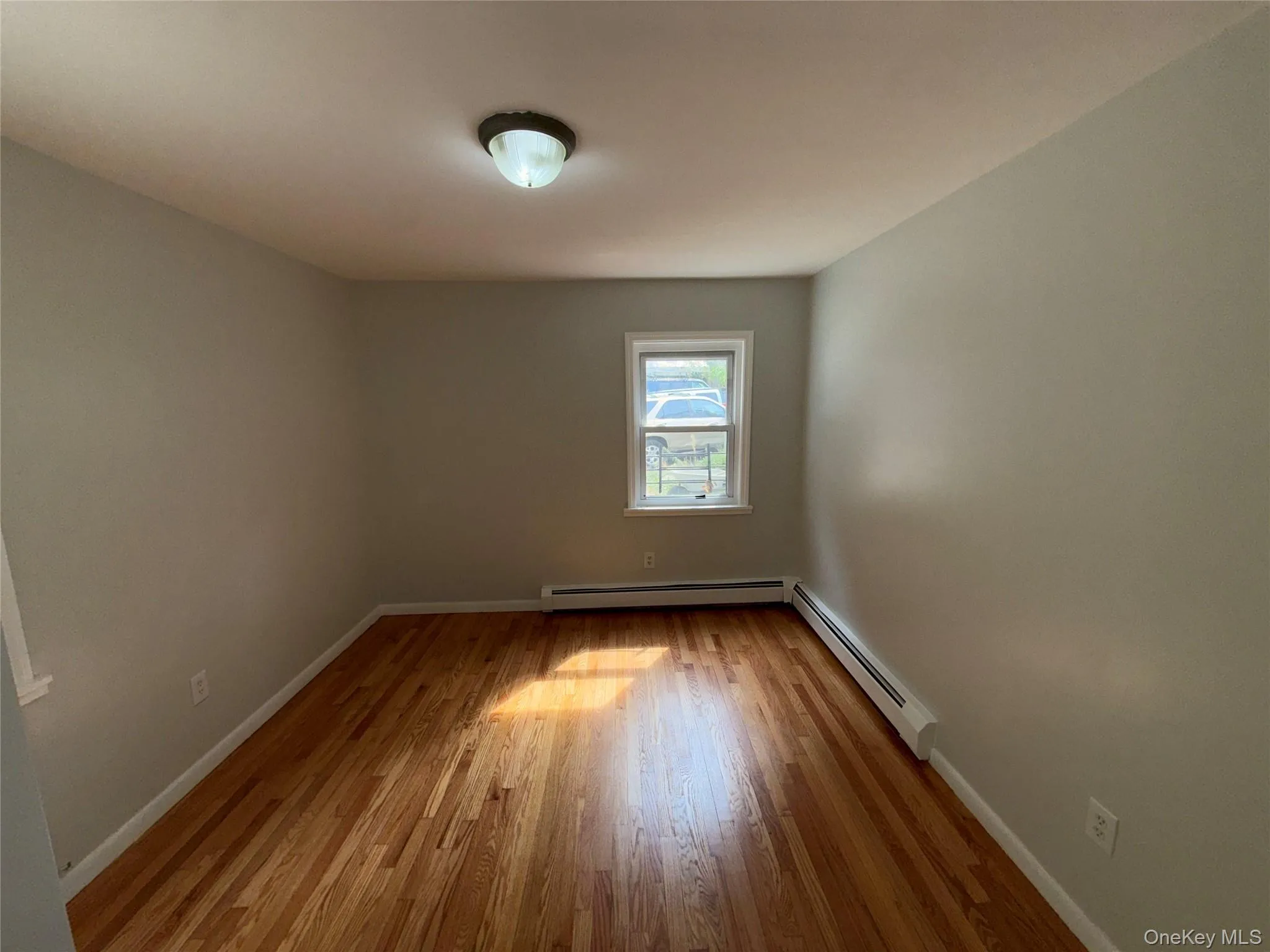 Spare room with light wood-style floors and a baseboard heating unit Spare room with light wood-style floors and a baseboard heating unit