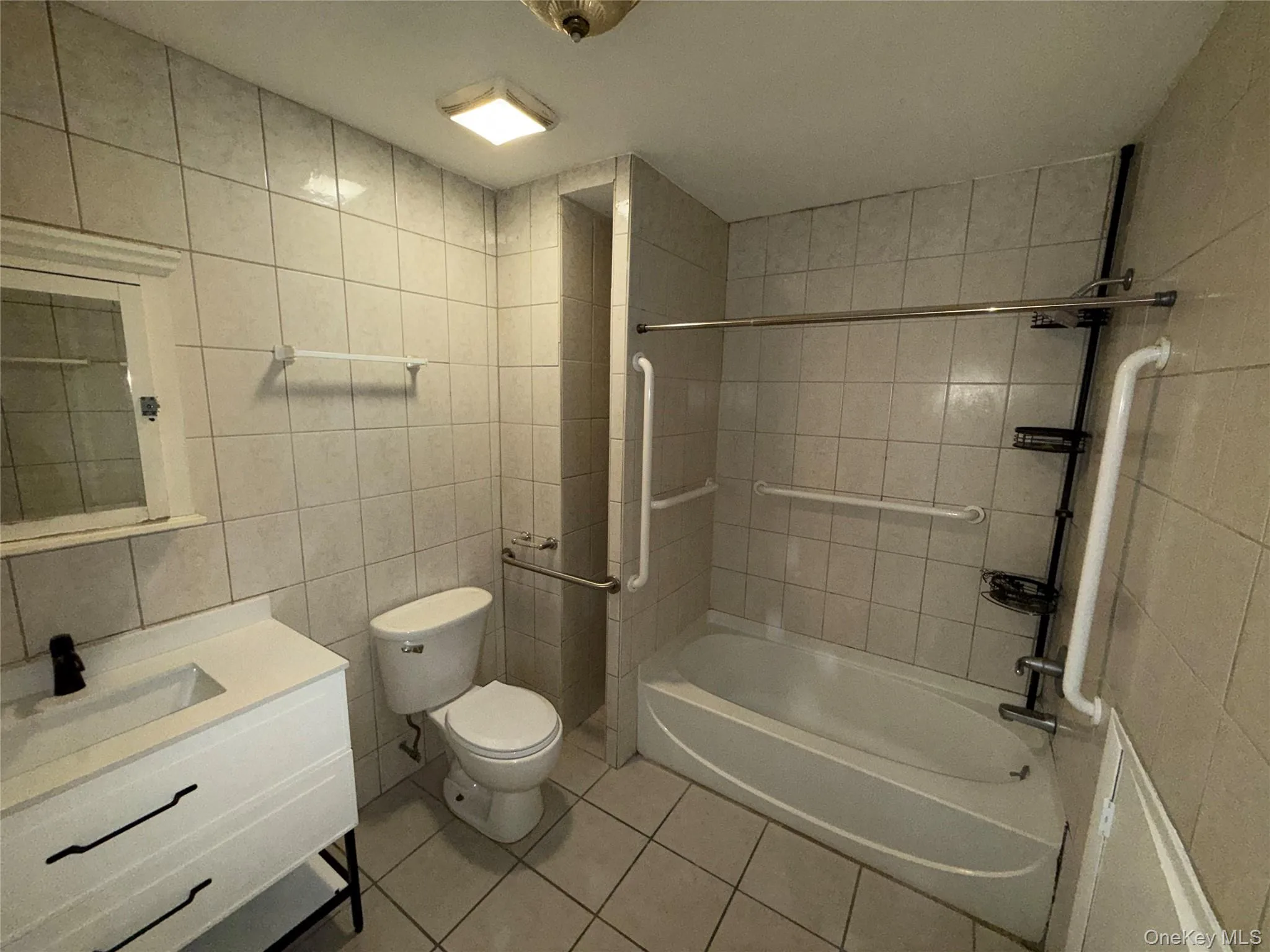 Full bathroom featuring tile walls, tile patterned floors, bathtub / shower combination, and vanity Full bathroom featuring tile walls, tile patterned floors, bathtub / shower combination, and vanity