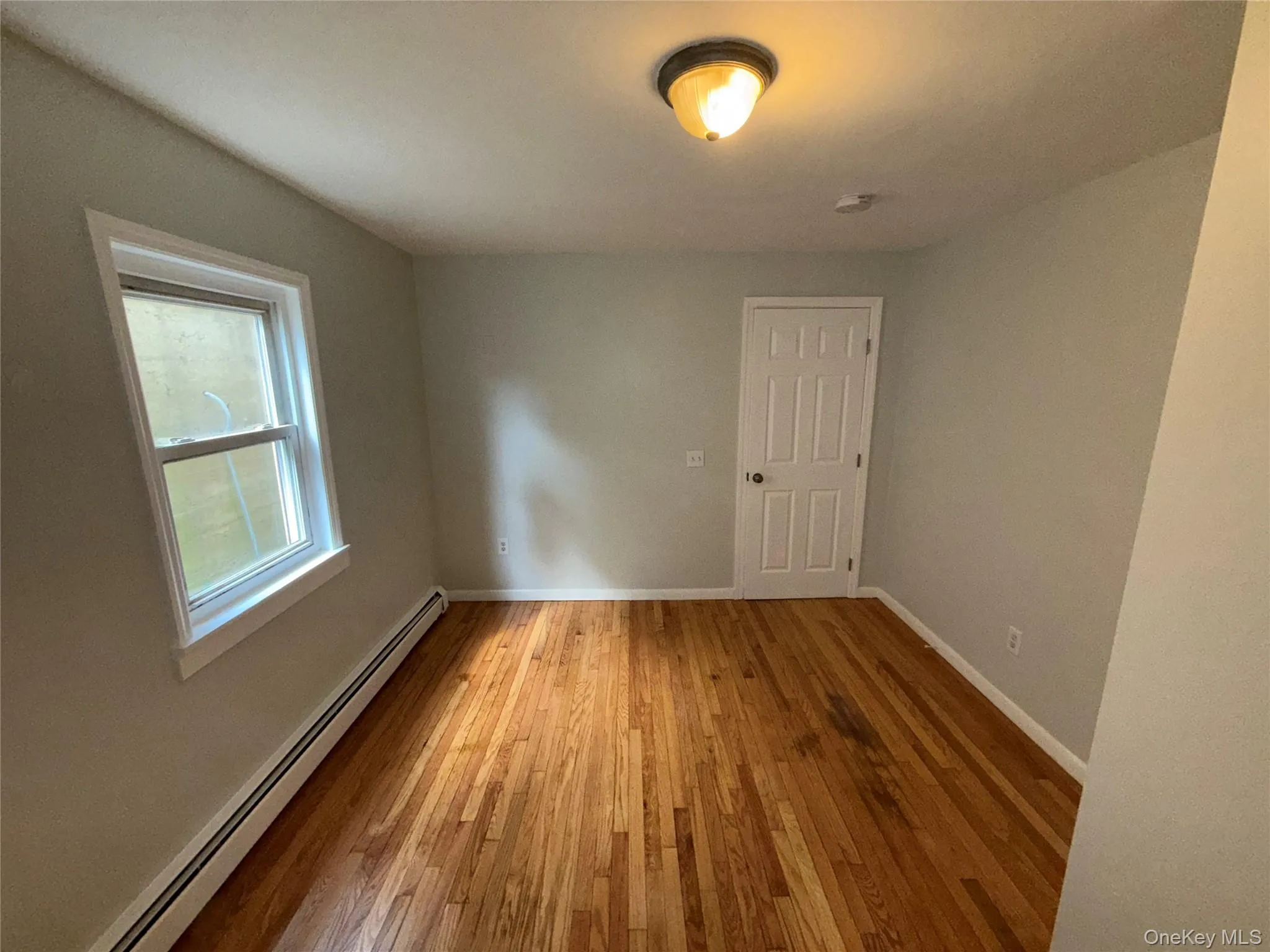 Spare room featuring baseboard heating and light wood finished floors Spare room featuring baseboard heating and light wood finished floors