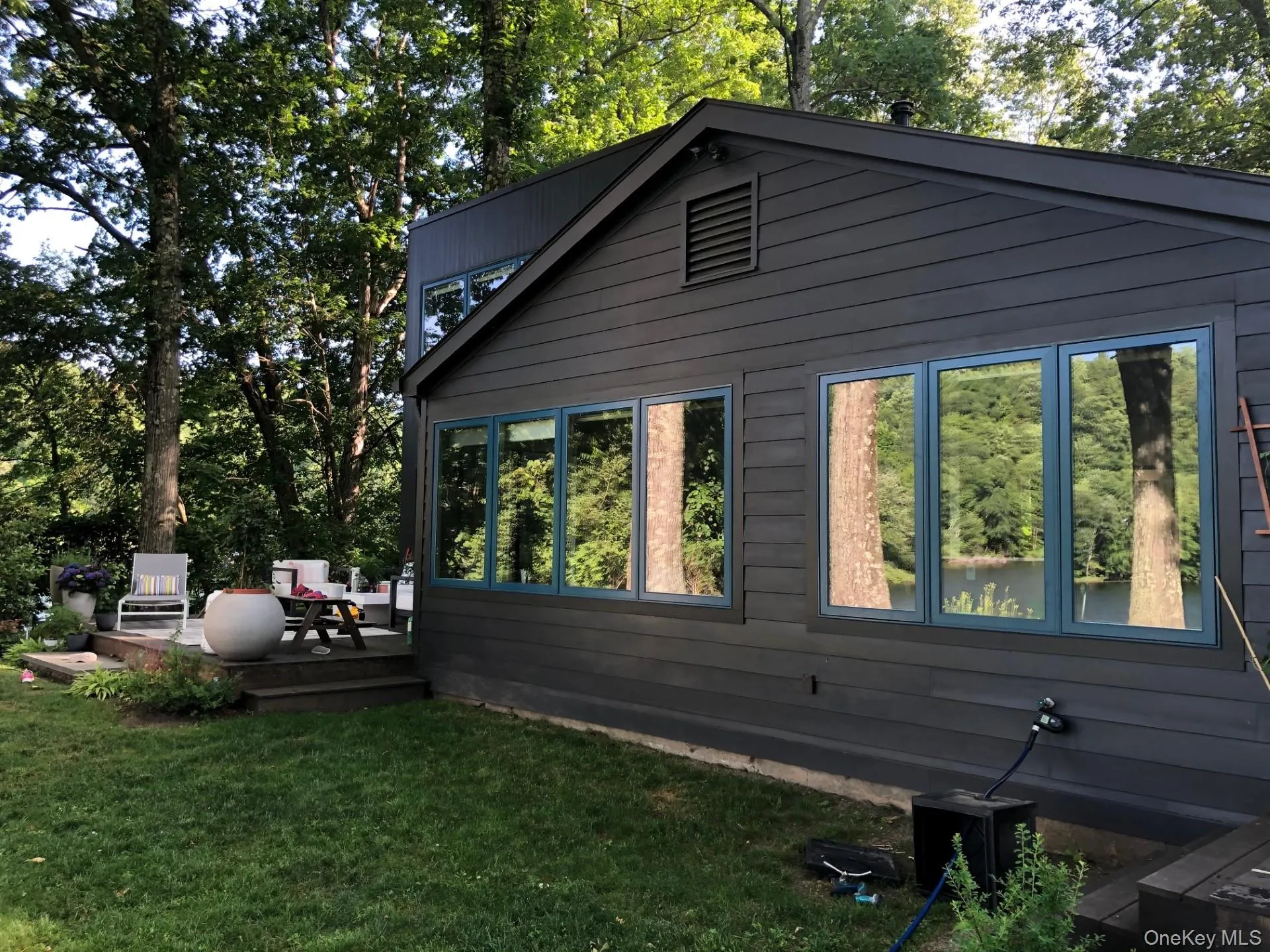 Side of home featuring a wooden deck, a yard with scattered trees, and an outdoor living space Side of home featuring a wooden deck, a yard with scattered trees, and an outdoor living space