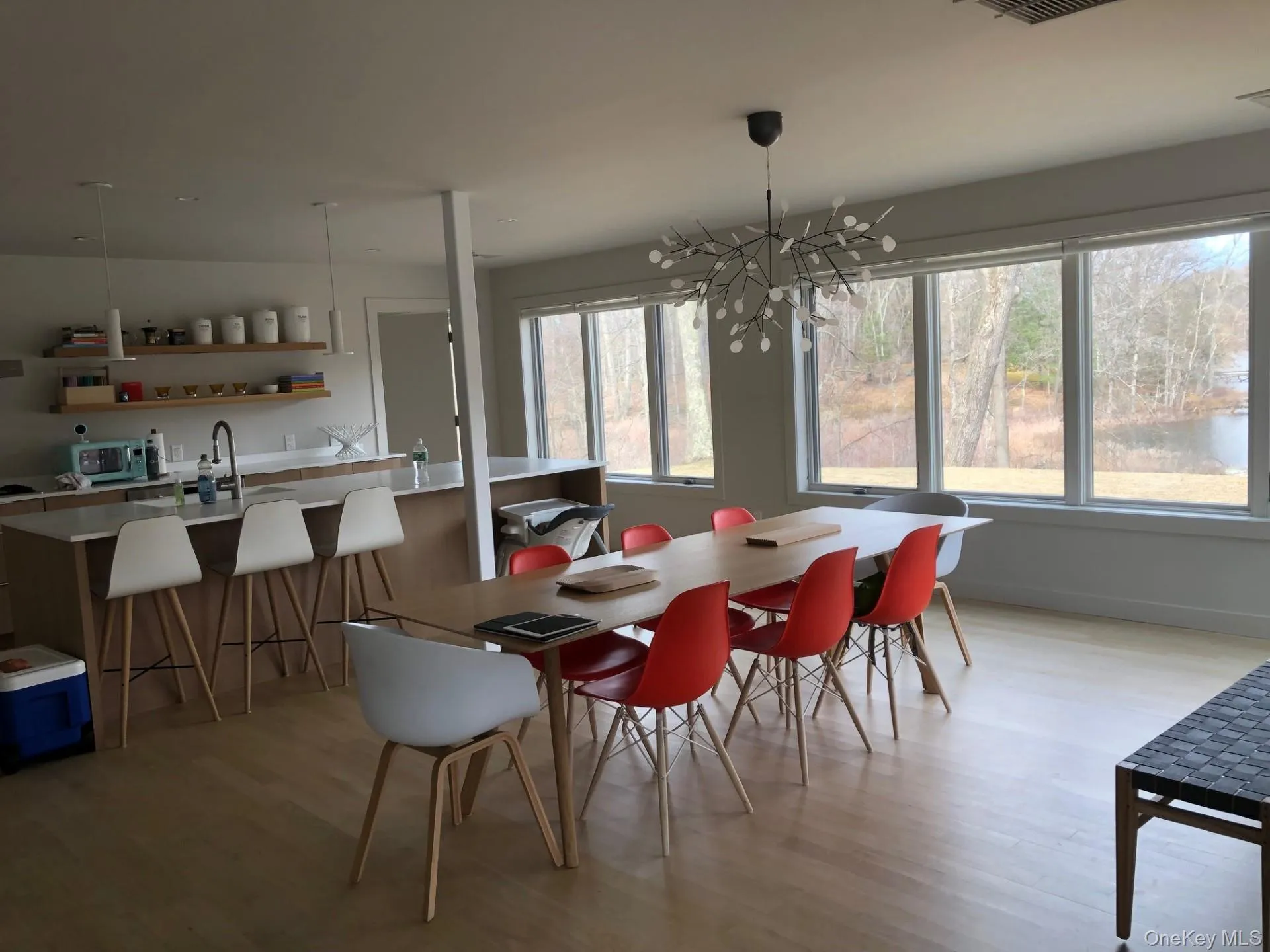 Dining area with light wood-style floors and a chandelier overlooking the lake Dining area with light wood-style floors and a chandelier overlooking the lake