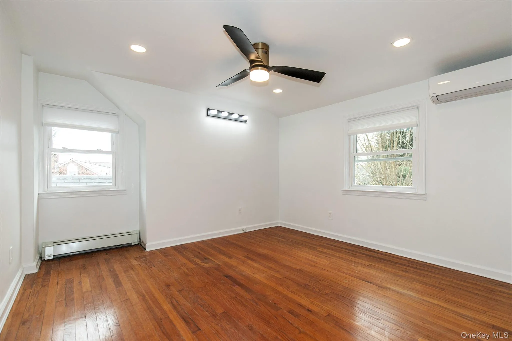 Spare room with a baseboard radiator, dark wood-style flooring, an AC wall unit, healthy amount of natural light, and recessed lighting Spare room with a baseboard radiator, dark wood-style flooring, an AC wall unit, healthy amount of natural light, and recessed lighting