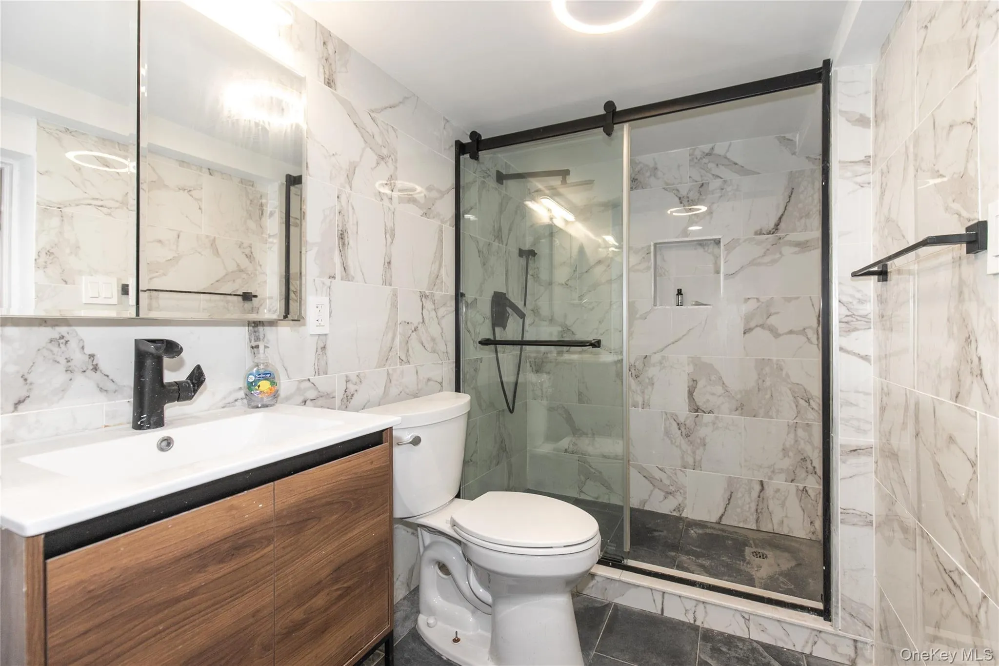 Full bathroom with tile walls, vanity, and a marble finish shower Full bathroom with tile walls, vanity, and a marble finish shower