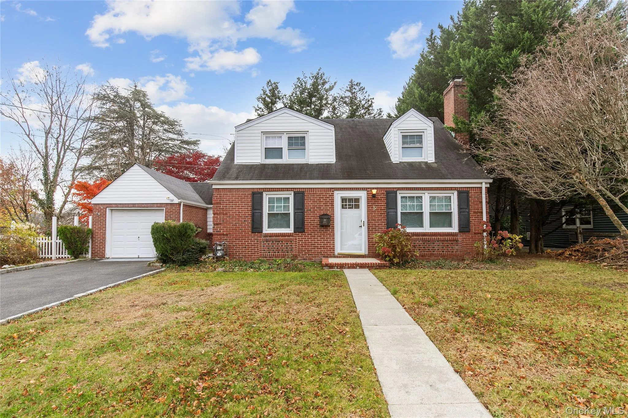 Cape cod house with a front lawn, brick siding, driveway, a chimney, and an outbuilding Cape cod house with a front lawn, brick siding, driveway, a chimney, and an outbuilding