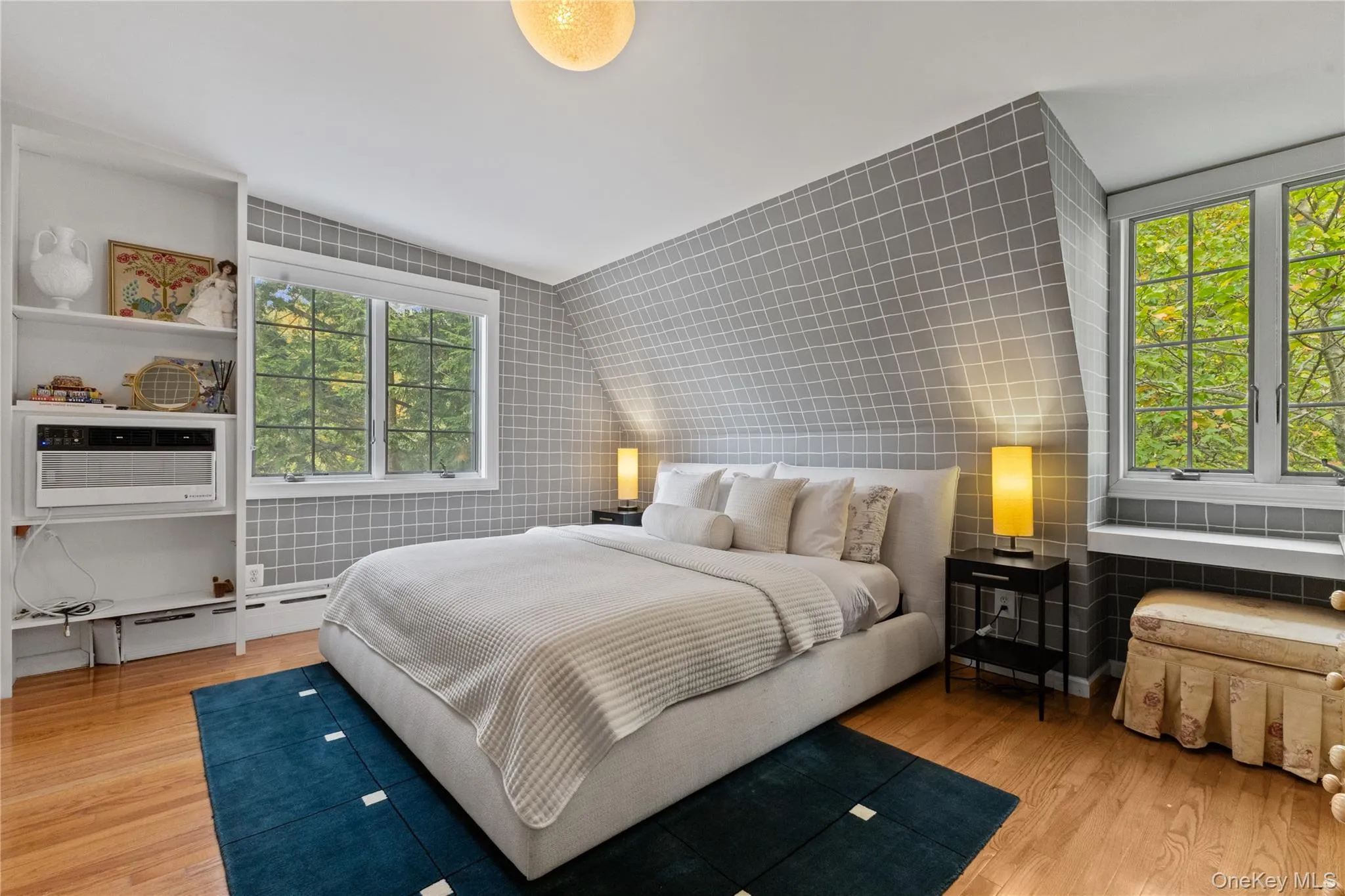 Bedroom with tile walls, multiple windows, light wood-style flooring, and baseboard heating Bedroom with tile walls, multiple windows, light wood-style flooring, and baseboard heating