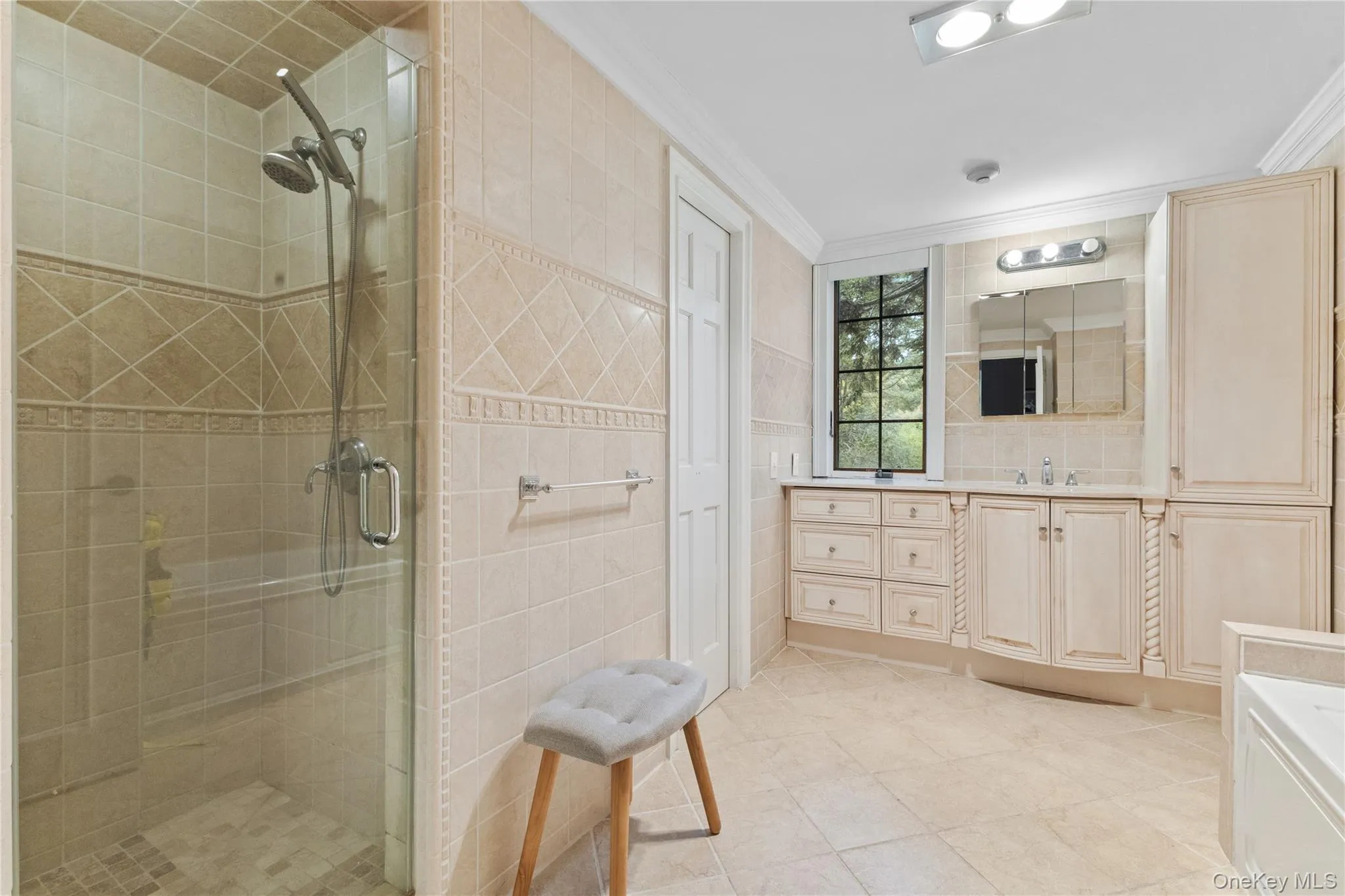 Bathroom featuring tile walls, vanity, a stall shower, light tile patterned floors, and crown molding Bathroom featuring tile walls, vanity, a stall shower, light tile patterned floors, and crown molding