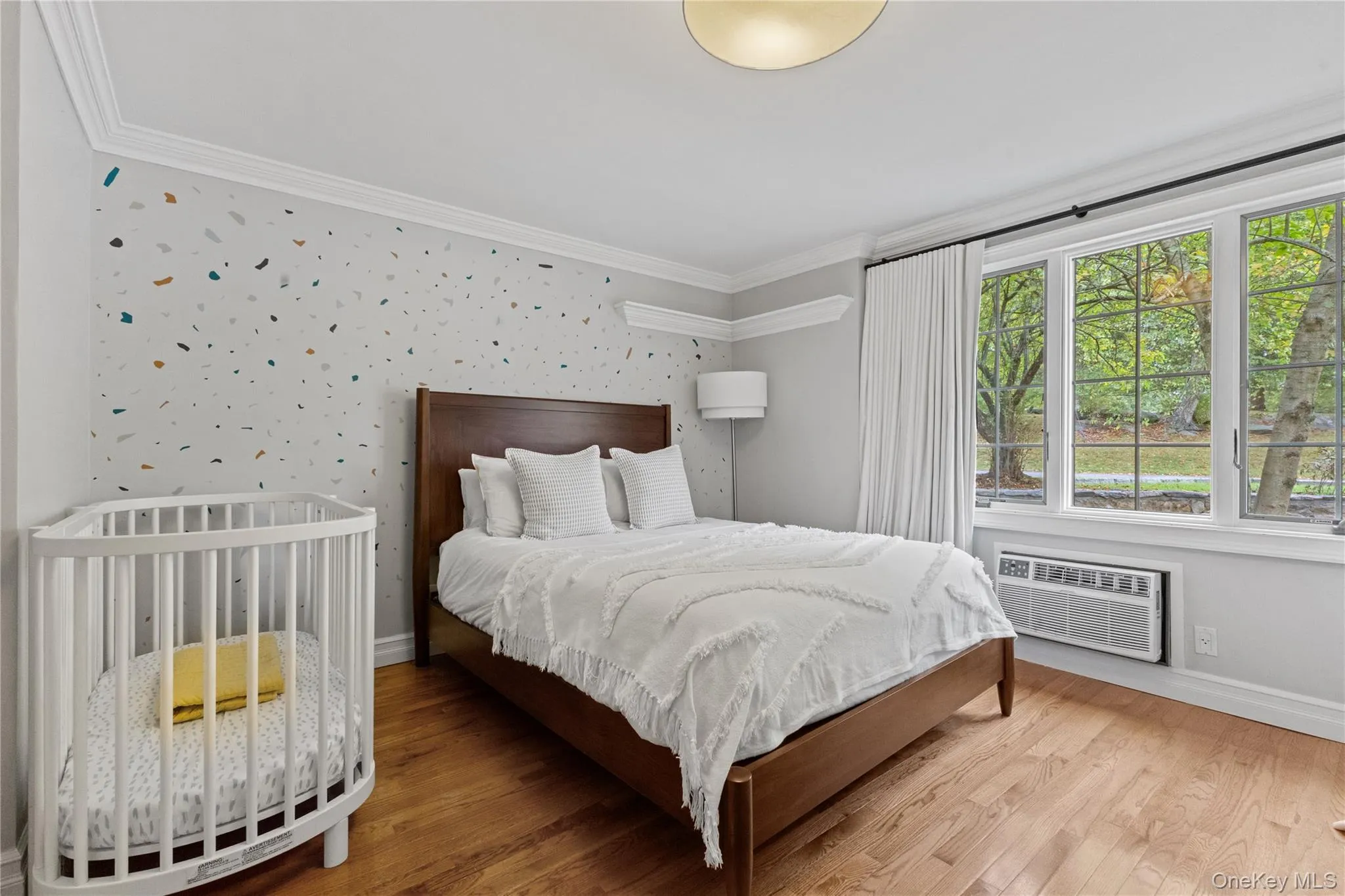 Bedroom featuring ornamental molding, wood finished floors, wallpapered walls, and a wall unit AC Bedroom featuring ornamental molding, wood finished floors, wallpapered walls, and a wall unit AC