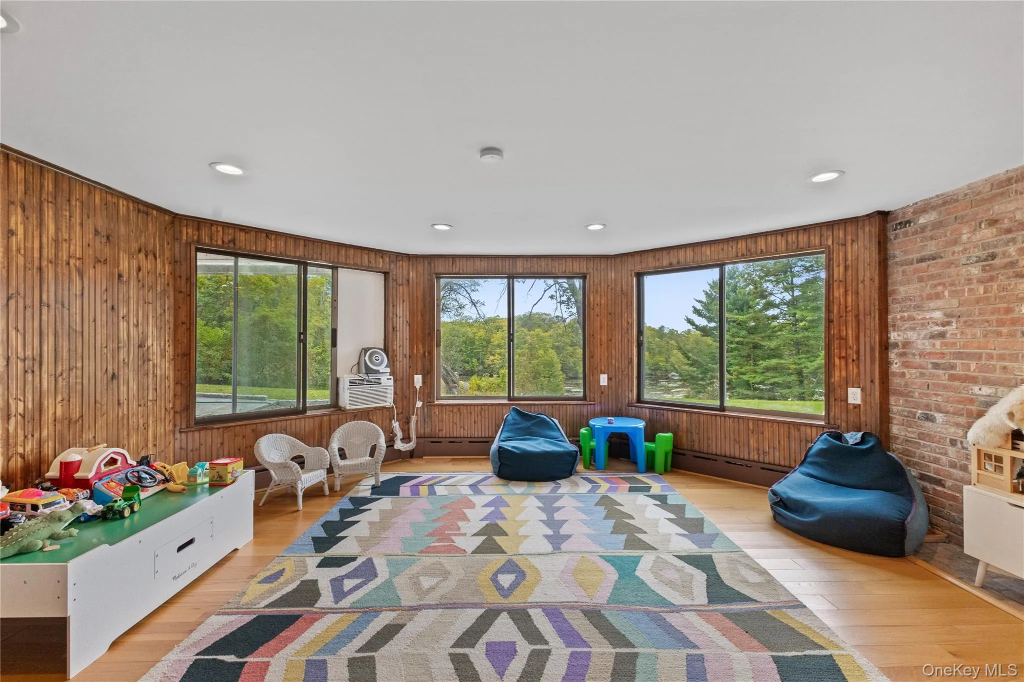 Playroom featuring wood finished floors, plenty of natural light, recessed lighting, baseboard heating, and wooden walls Playroom featuring wood finished floors, plenty of natural light, recessed lighting, baseboard heating, and wooden walls