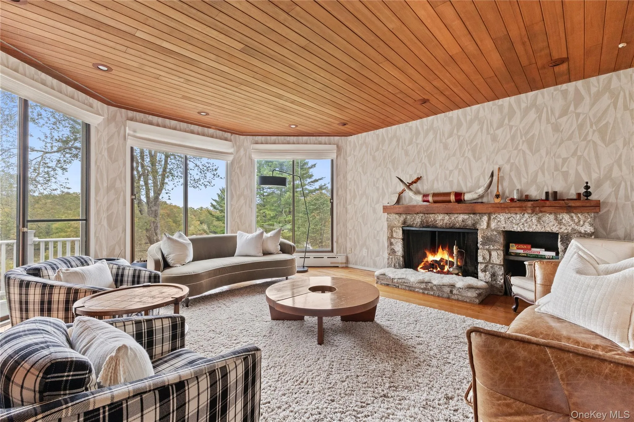 Living room with wooden ceiling, wood finished floors, wallpapered walls, a fireplace, and baseboard heating Living room with wooden ceiling, wood finished floors, wallpapered walls, a fireplace, and baseboard heating