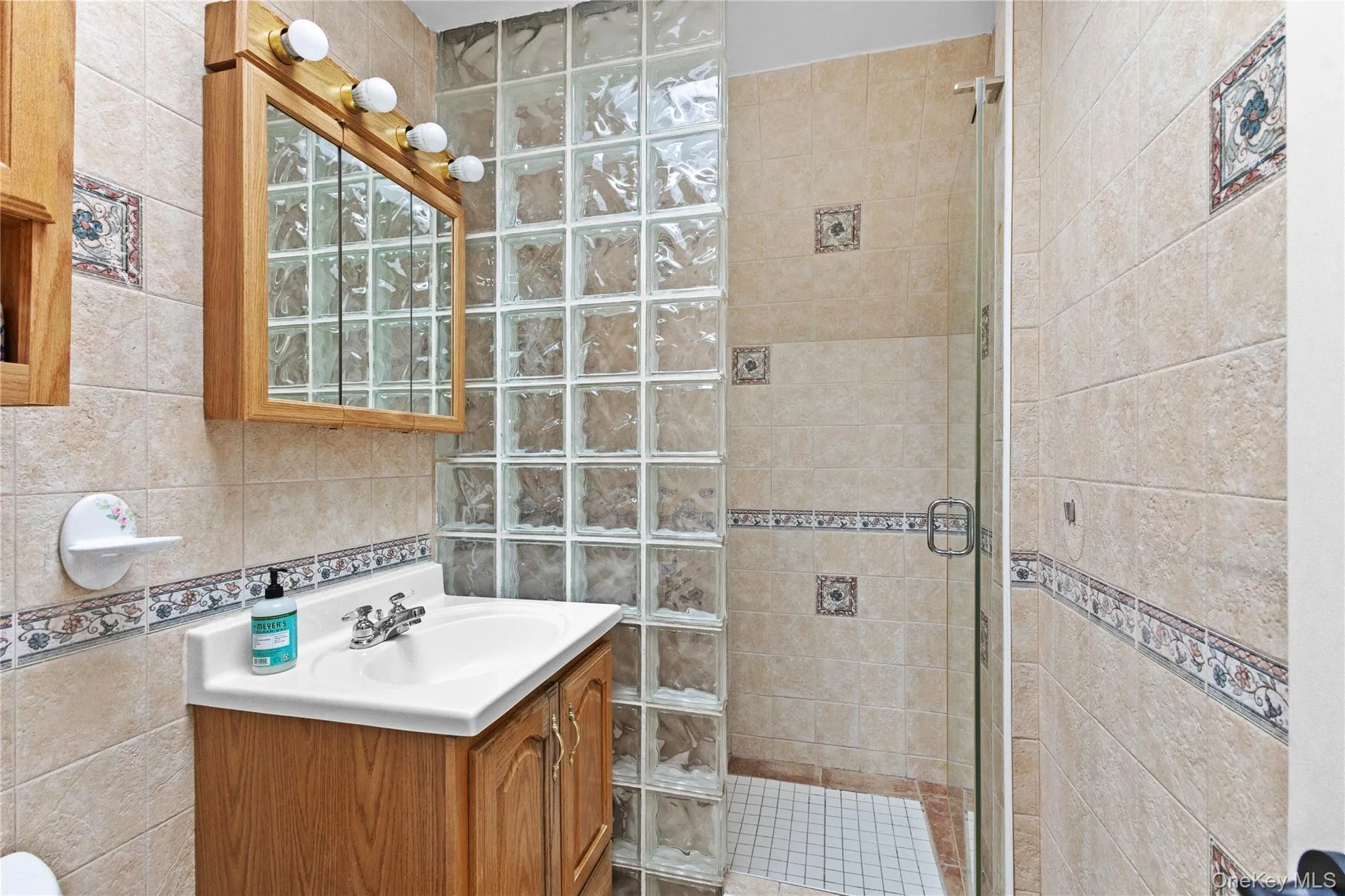 Bathroom with vanity, a shower stall, and tile walls Bathroom with vanity, a shower stall, and tile walls