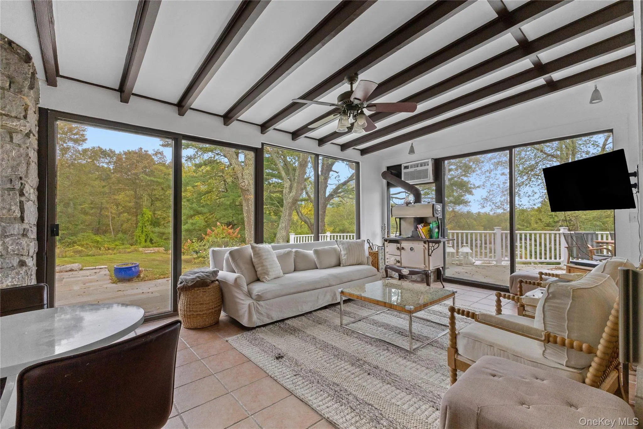 Sunroom / solarium with tile patterned floors, an outdoor living space, a ceiling fan, and beam ceiling Sunroom / solarium with tile patterned floors, an outdoor living space, a ceiling fan, and beam ceiling