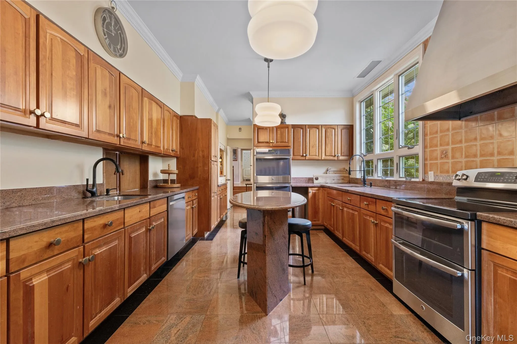 Kitchen with appliances with stainless steel finishes, custom exhaust hood, brown cabinetry, crown molding, and a breakfast bar Kitchen with appliances with stainless steel finishes, custom exhaust hood, brown cabinetry, crown molding, and a breakfast bar