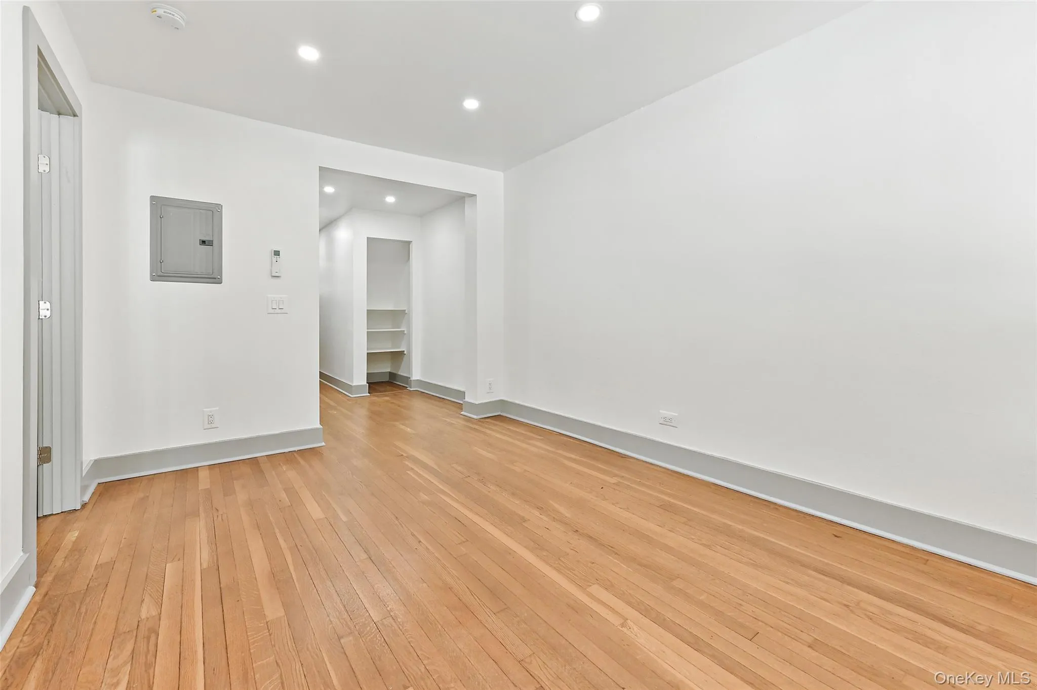 Empty room featuring recessed lighting, light wood-style floors, and electric panel Empty room featuring recessed lighting, light wood-style floors, and electric panel