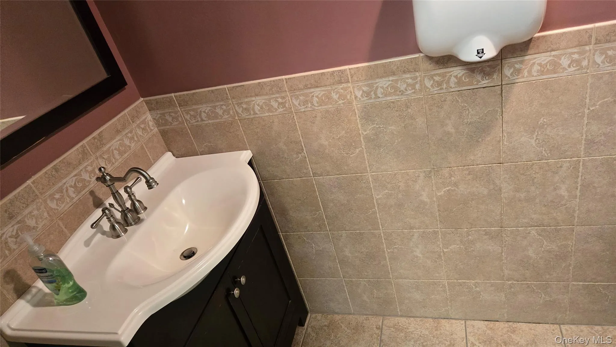 Bathroom with vanity, tile walls, a wainscoted wall, and tile patterned flooring Bathroom with vanity, tile walls, a wainscoted wall, and tile patterned flooring