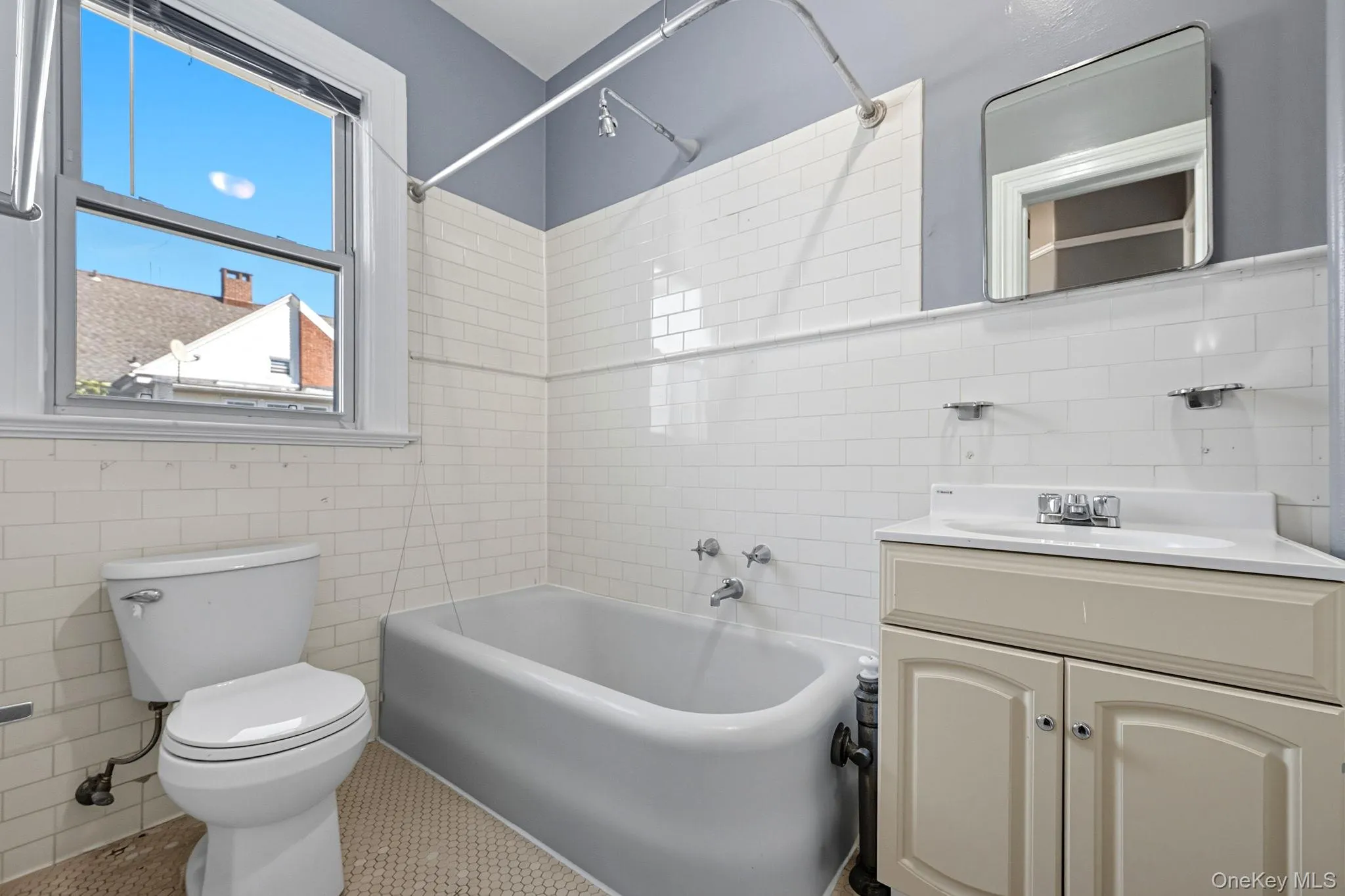 Bathroom with tile walls, shower / washtub combination, vanity, and tile patterned flooring Bathroom with tile walls, shower / washtub combination, vanity, and tile patterned flooring