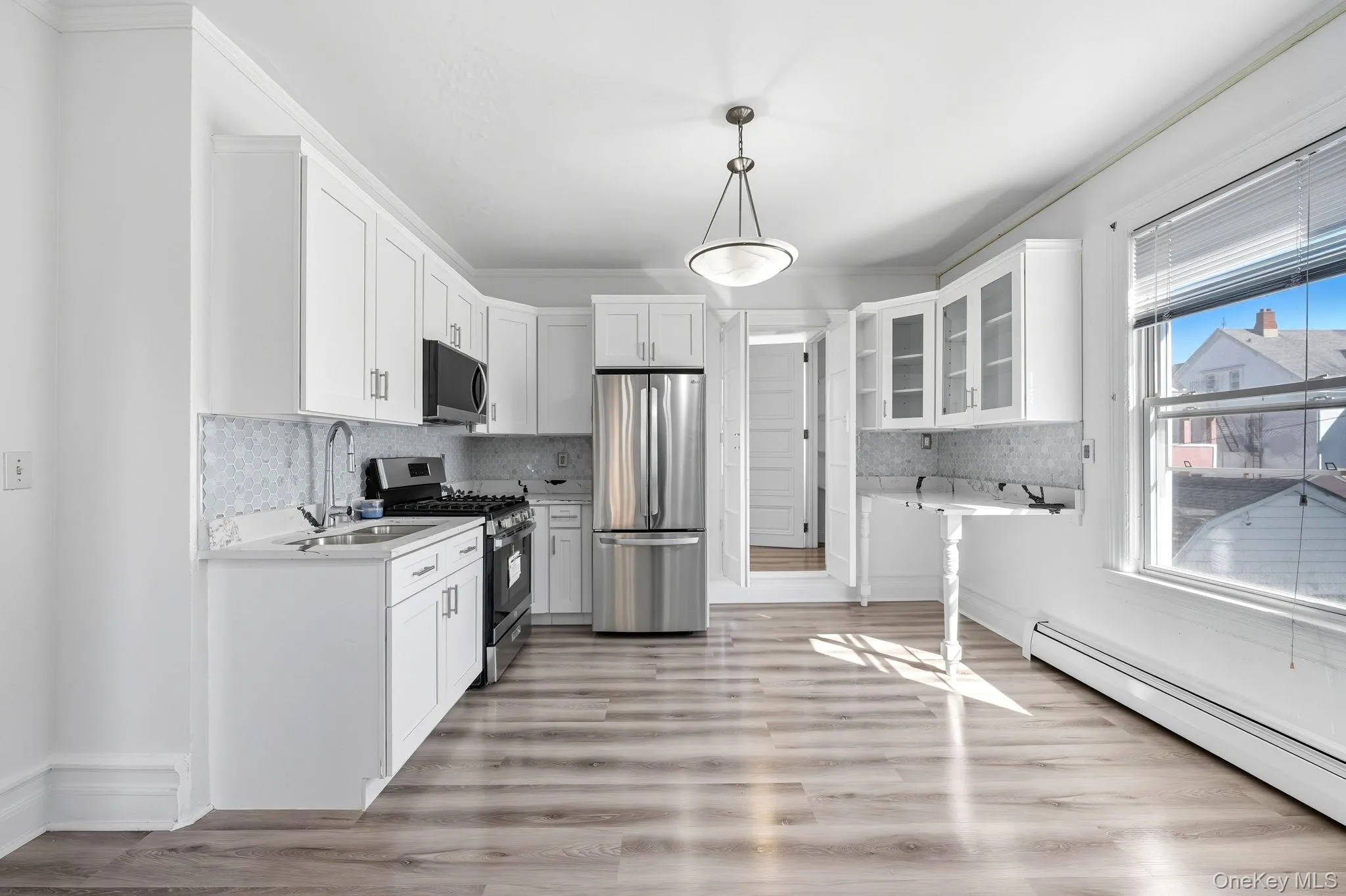 Kitchen with glass insert cabinets, stainless steel appliances, tasteful backsplash, white cabinetry, and ornamental molding Kitchen with glass insert cabinets, stainless steel appliances, tasteful backsplash, white cabinetry, and ornamental molding