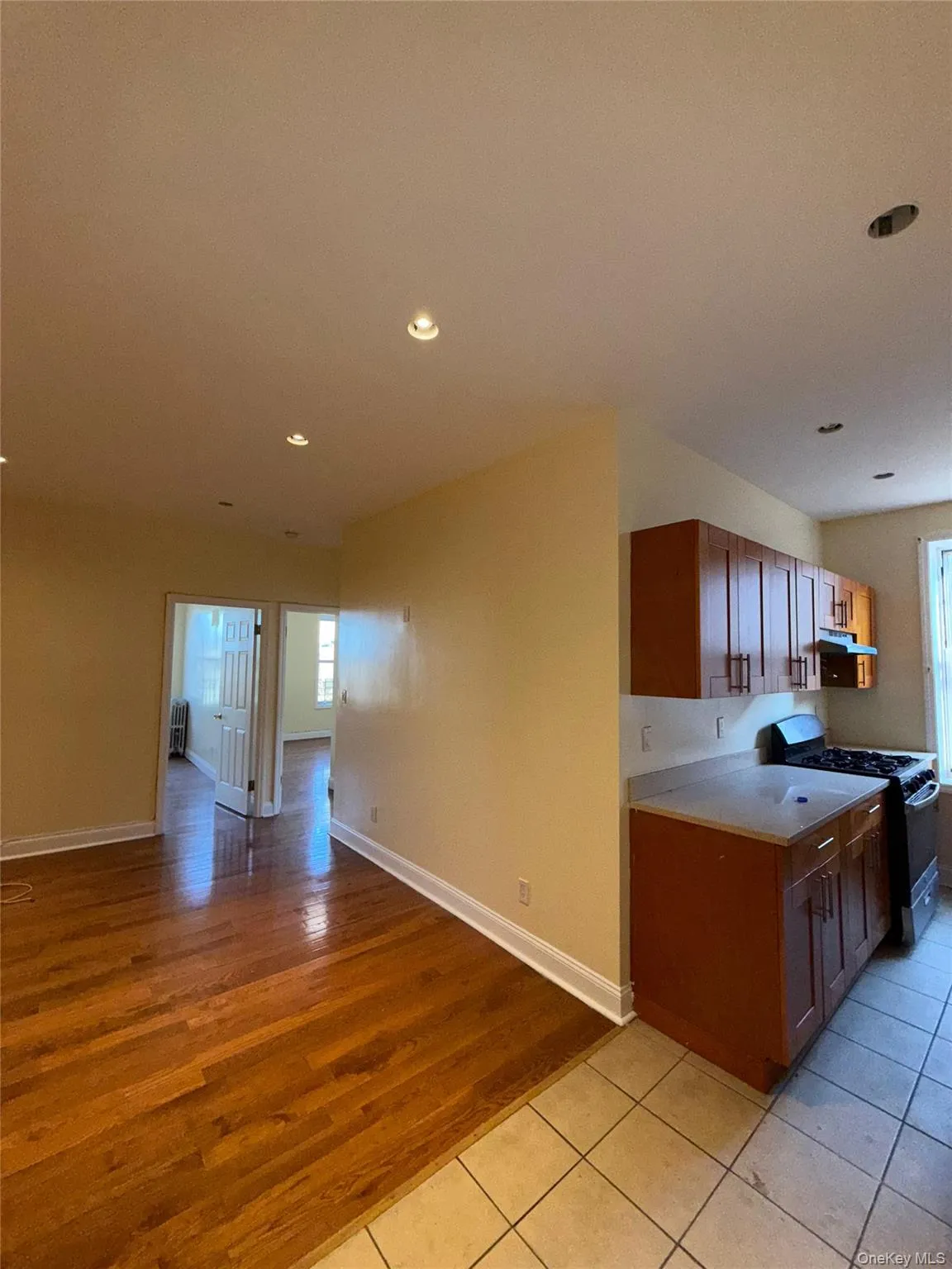 Kitchen featuring brown cabinets, black gas range, open floor plan, light tile patterned floors, and recessed lighting Kitchen featuring brown cabinets, black gas range, open floor plan, light tile patterned floors, and recessed lighting