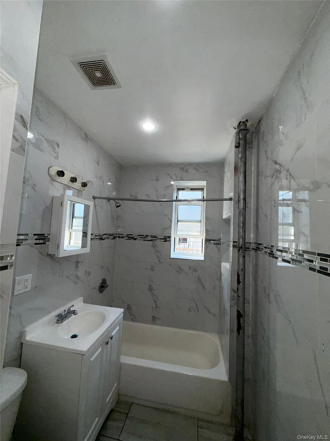 Full bathroom with tile walls, vanity, and bathtub / shower combination Full bathroom with tile walls, vanity, and bathtub / shower combination