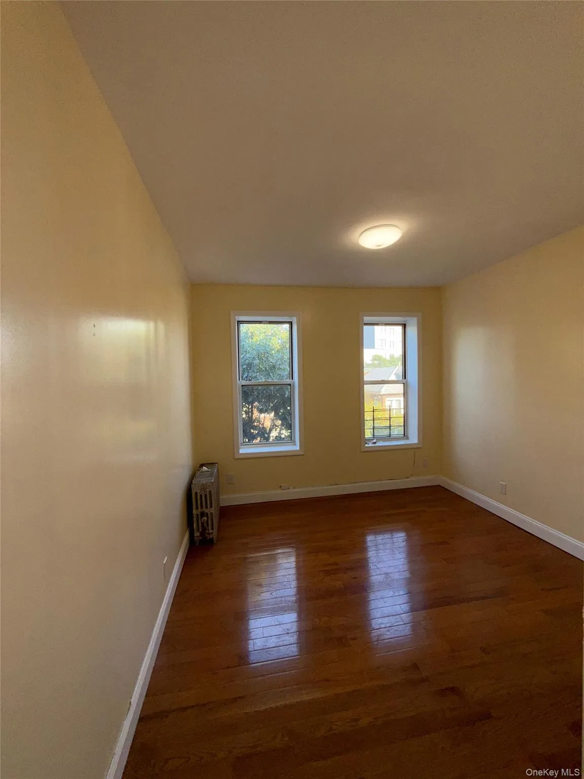 Spare room featuring dark wood finished floors and radiator Spare room featuring dark wood finished floors and radiator