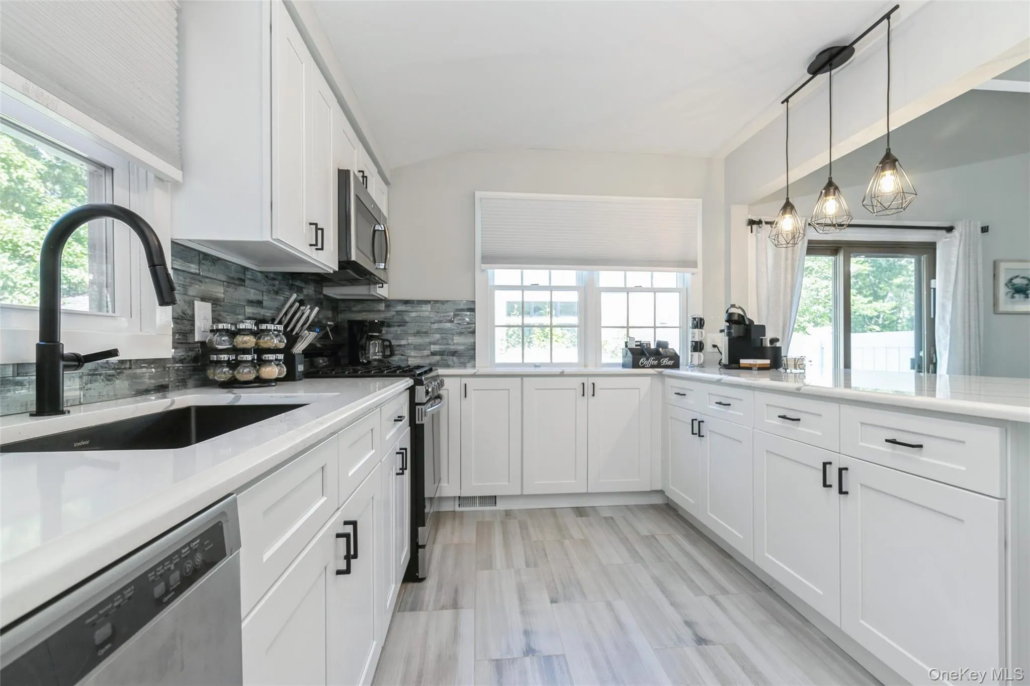 Kitchen featuring white cabinets, stainless steel appliances, healthy amount of natural light, and lofted ceiling Kitchen featuring white cabinets, stainless steel appliances, healthy amount of natural light, and lofted ceiling