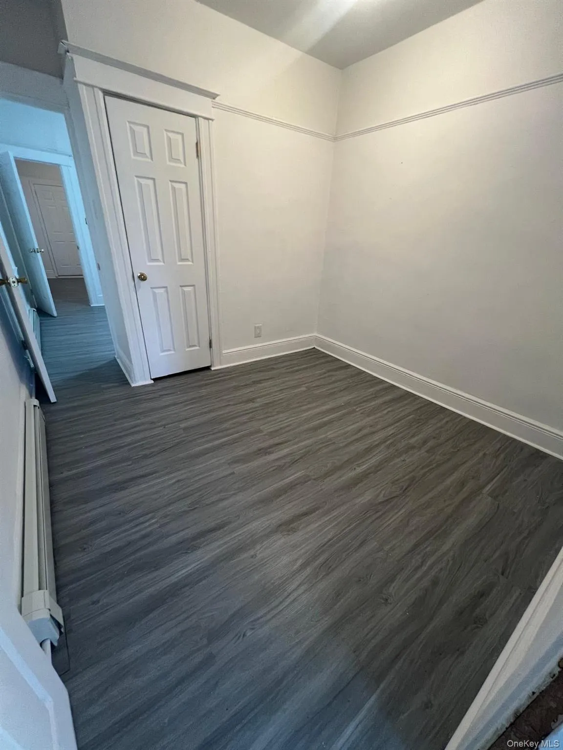 Unfurnished bedroom featuring dark wood-style floors and baseboards Unfurnished bedroom featuring dark wood-style floors and baseboards