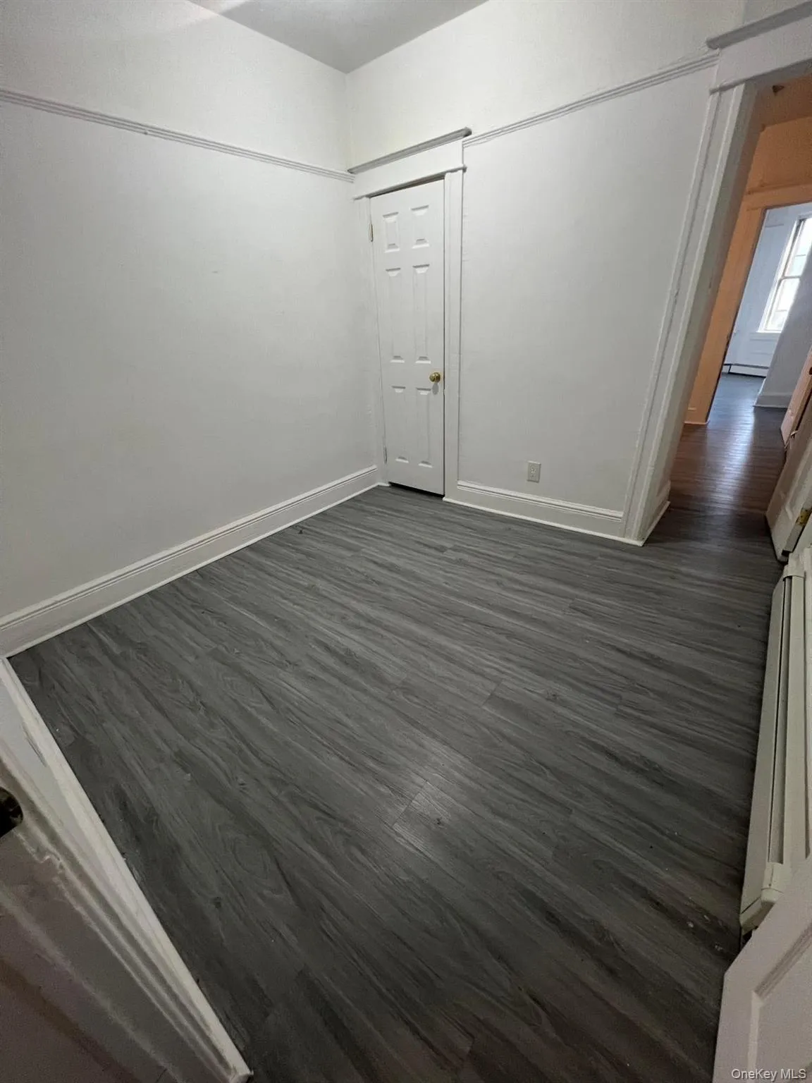 Unfurnished room featuring dark wood-style flooring and baseboards Unfurnished room featuring dark wood-style flooring and baseboards