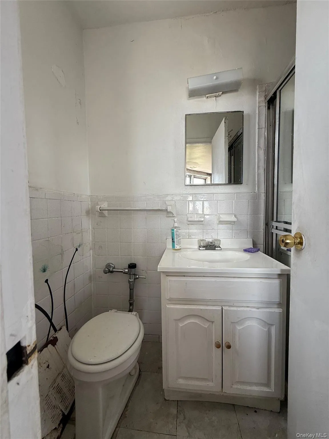 Half bathroom featuring vanity, tile walls, and a wainscoted wall Half bathroom featuring vanity, tile walls, and a wainscoted wall