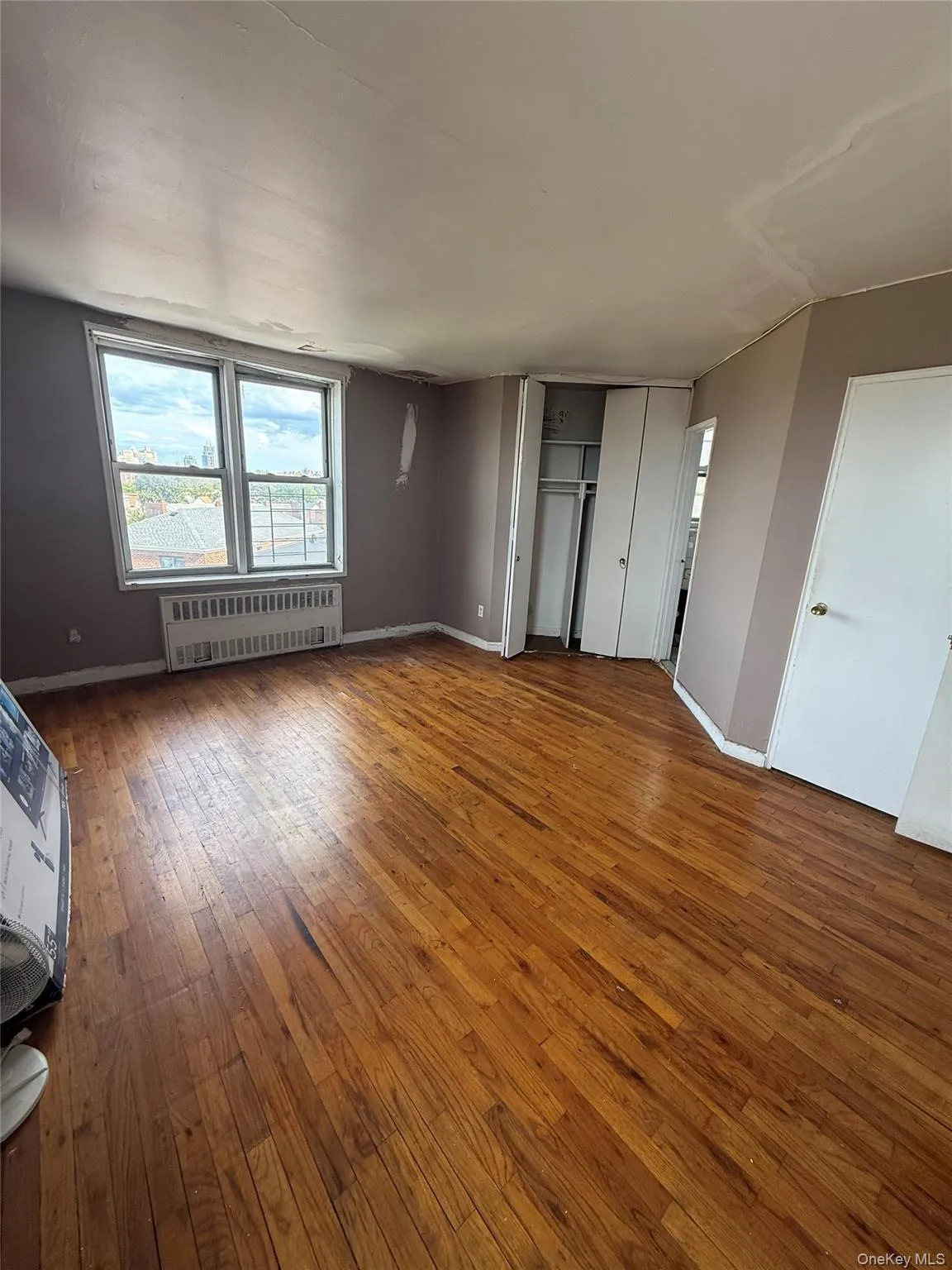 Unfurnished bedroom with hardwood / wood-style flooring, radiator heating unit, and a closet Unfurnished bedroom with hardwood / wood-style flooring, radiator heating unit, and a closet