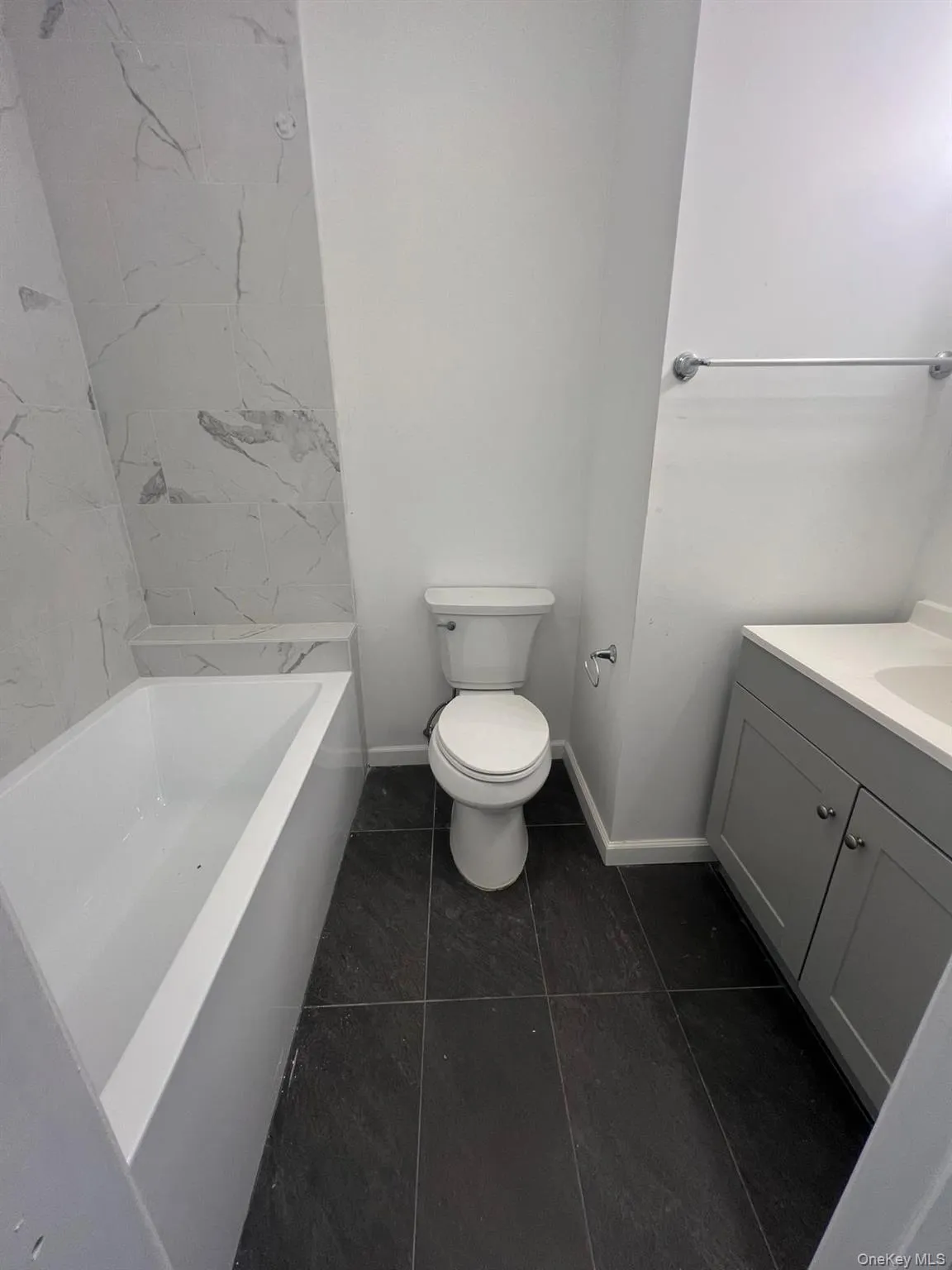 Bathroom featuring vanity, dark tile patterned floors, and  shower combination Bathroom featuring vanity, dark tile patterned floors, and  shower combination