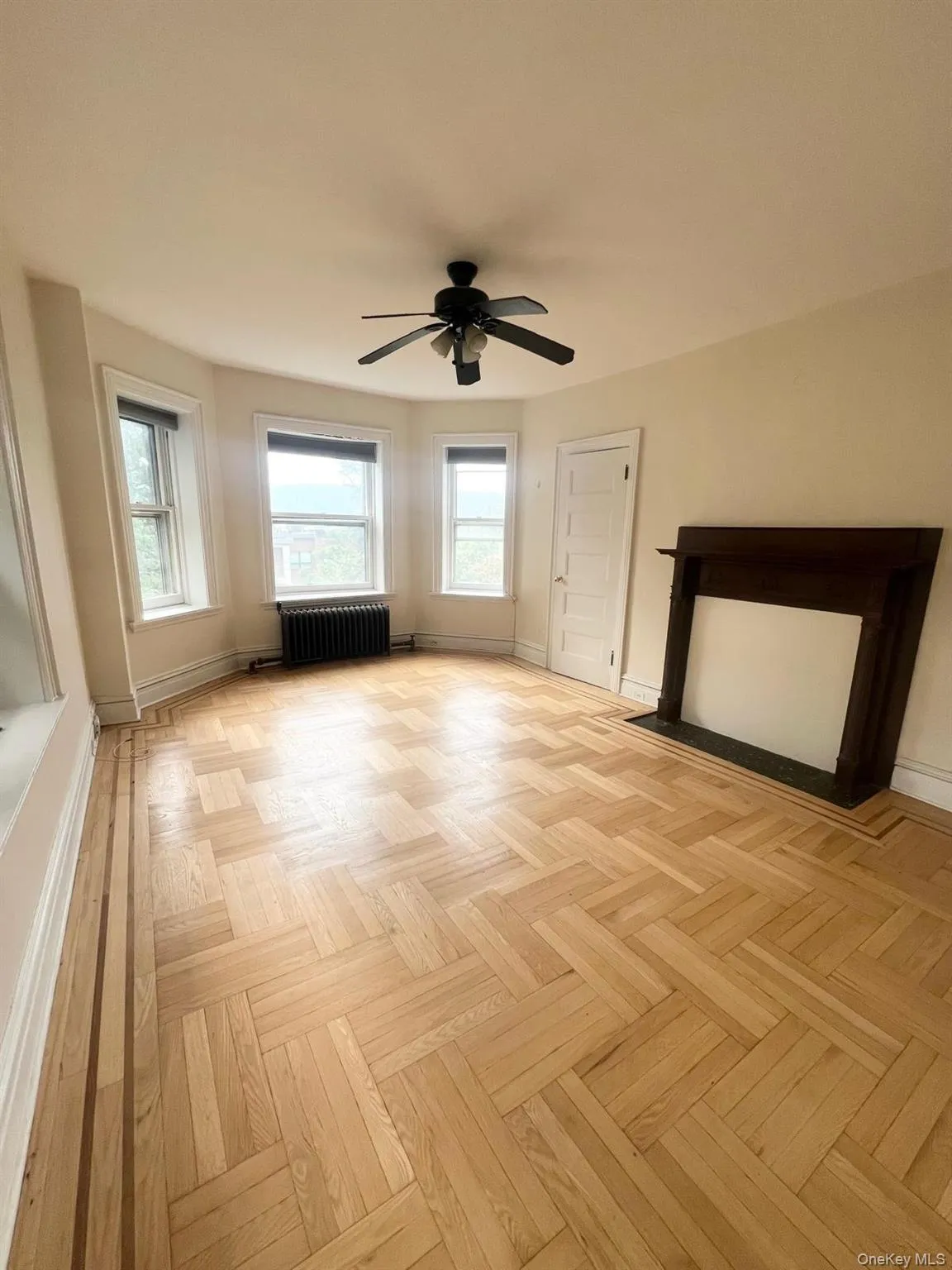 Unfurnished living room featuring radiator and ceiling fan Unfurnished living room featuring radiator and ceiling fan